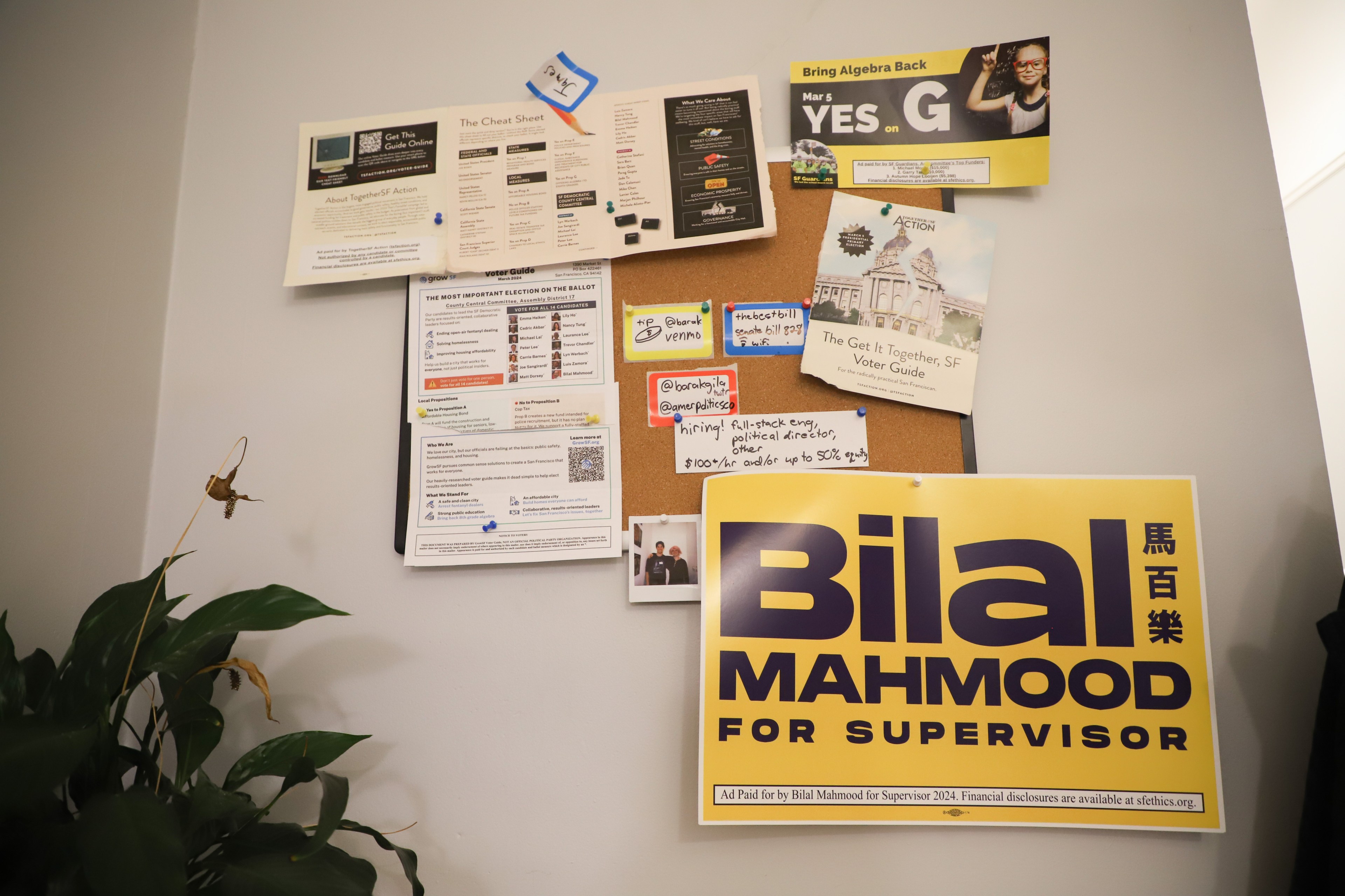 A bulletin board is covered with flyers, notes, and a political signs.