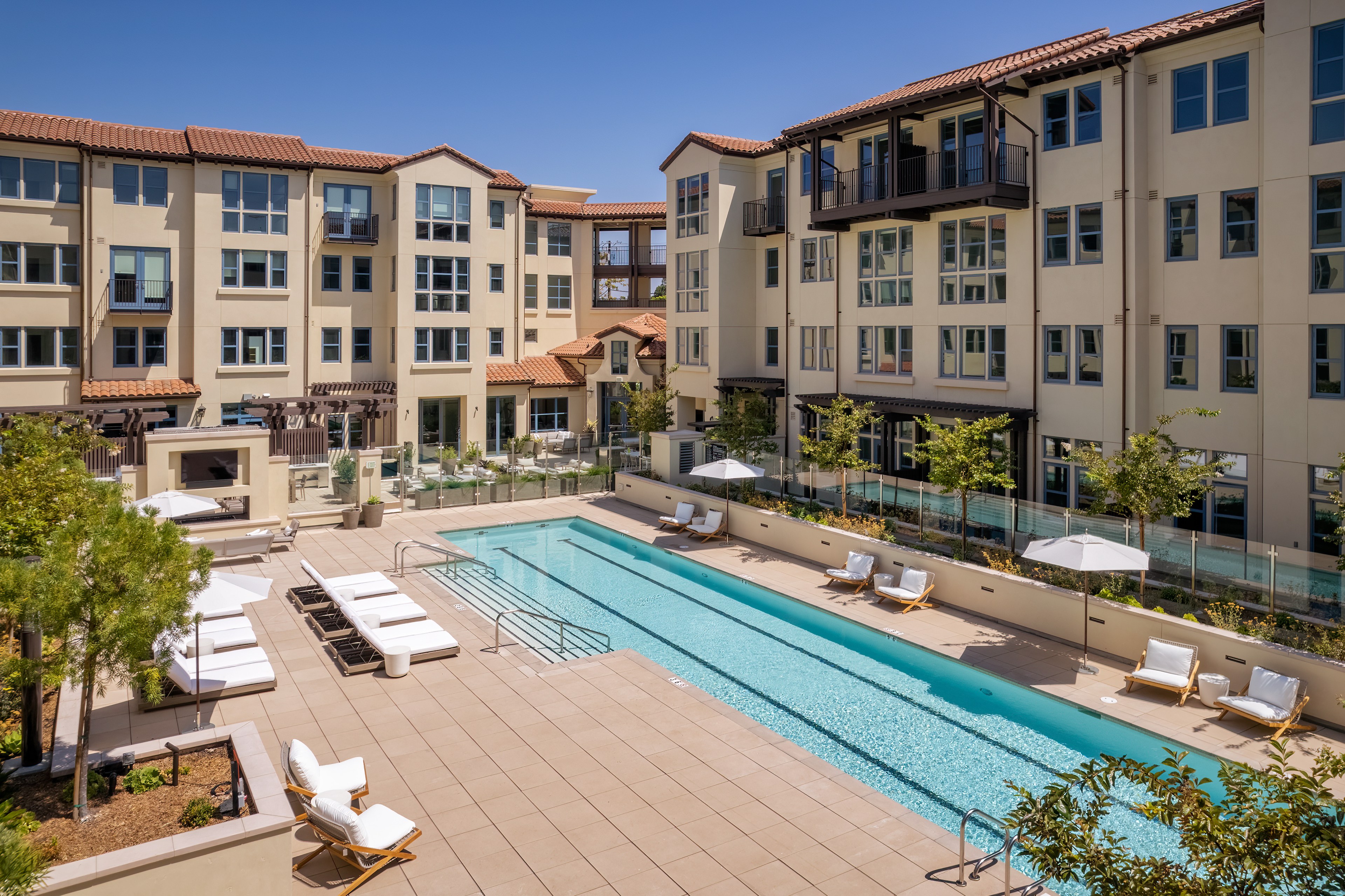 A serene pool area with loungers set before a multi-story residential building.