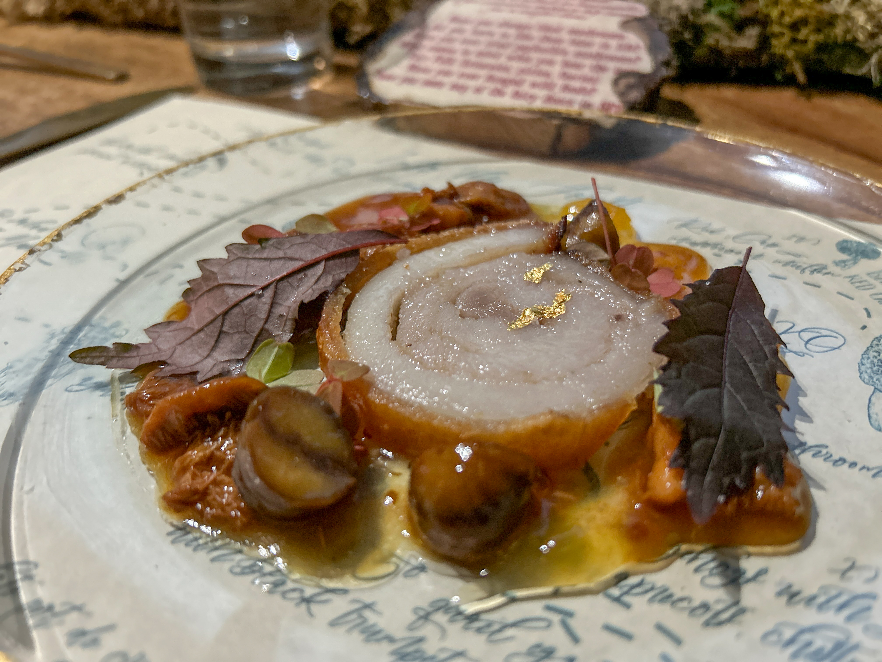 A gourmet dish with onion slices, mushrooms, and leaves on a decorative plate.