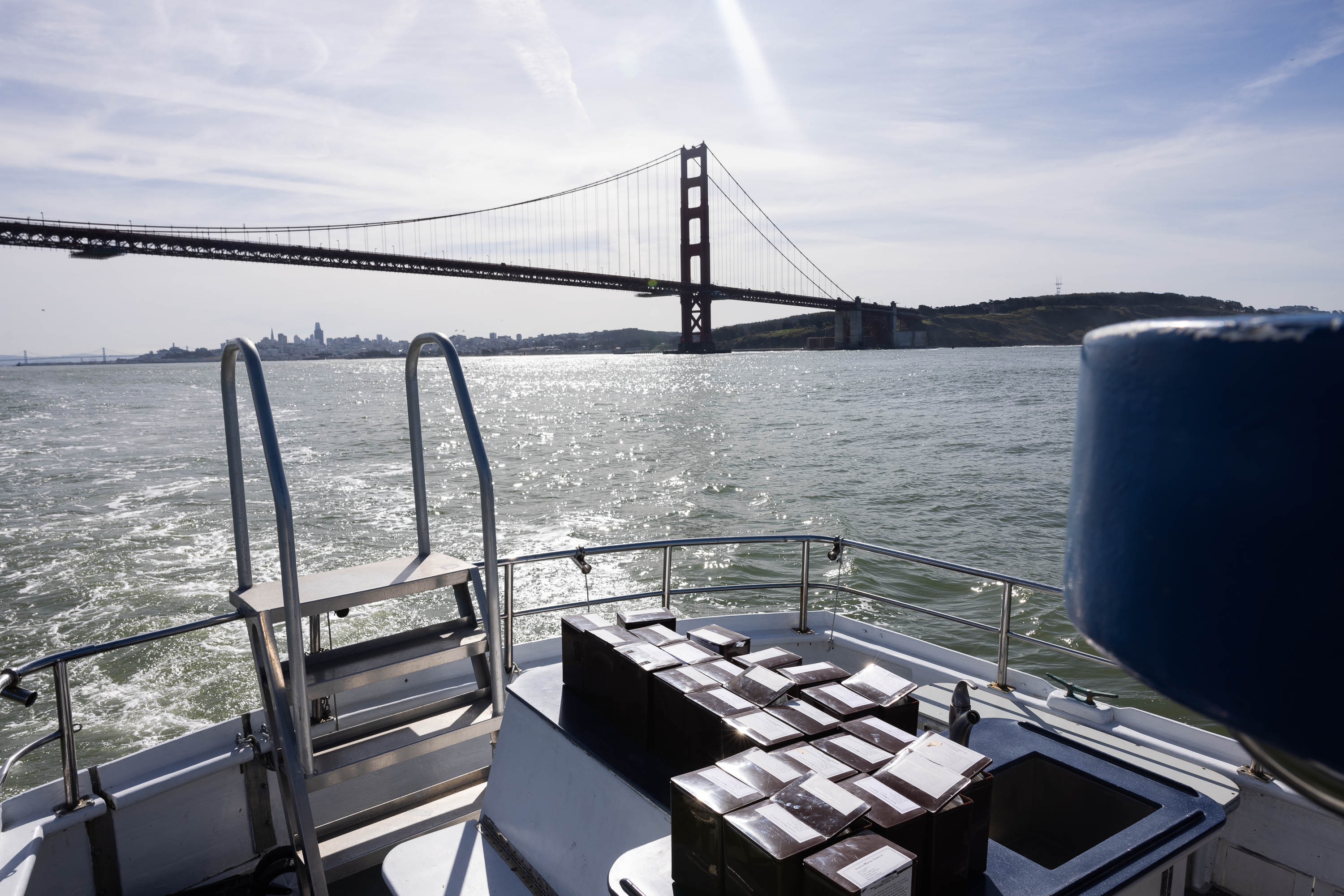A boat's rear deck with empty seats overlooking the Golden Gate Bridge and San Francisco skyline.