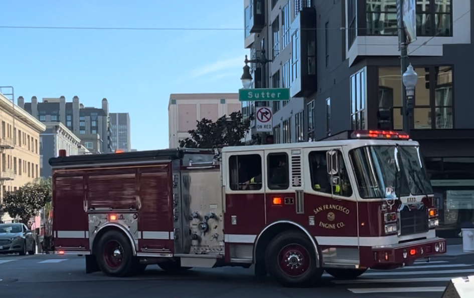 A fire truck turns through an intersection in a city.