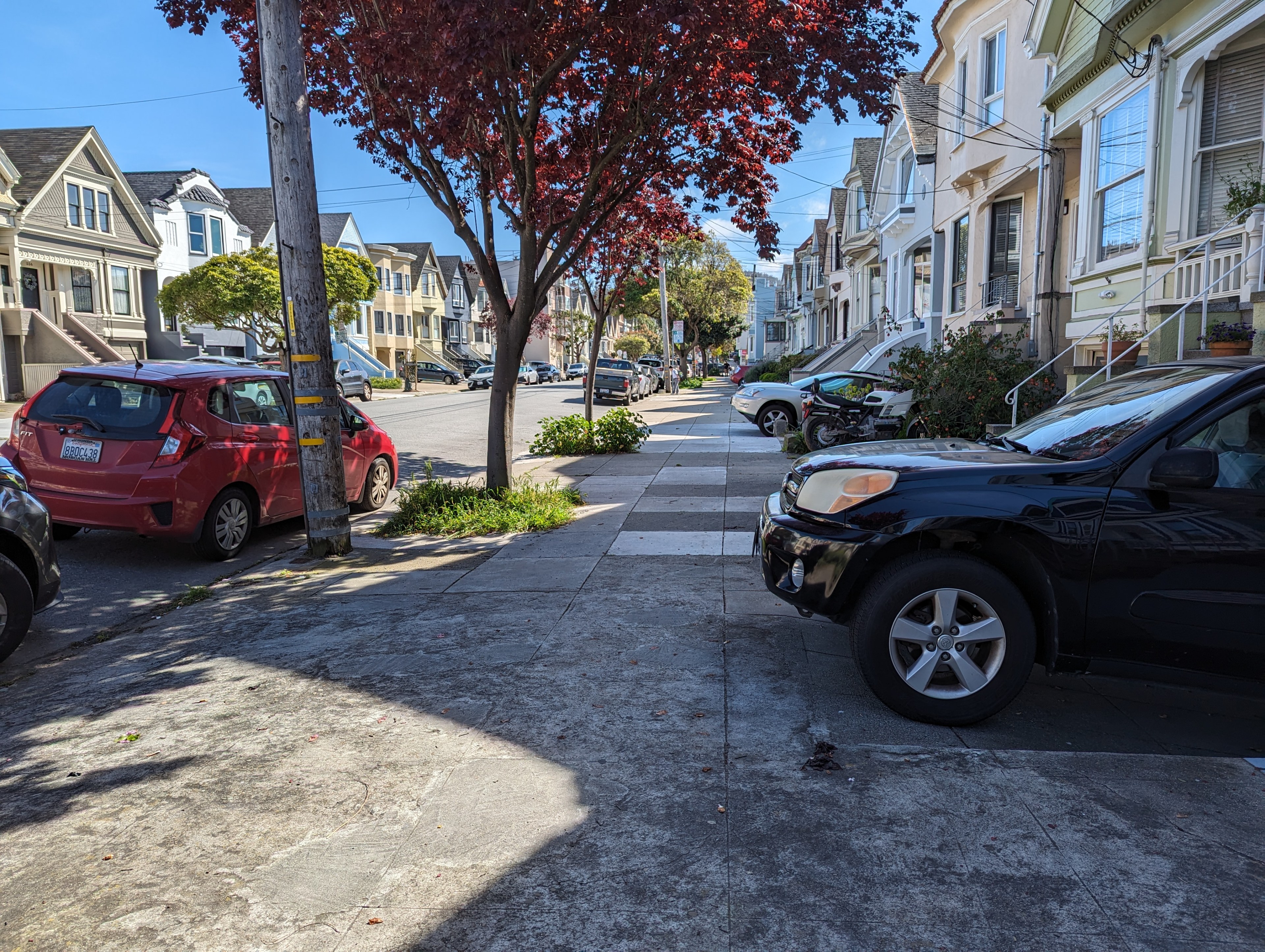A line of cars are parked in driveways on a residential street.