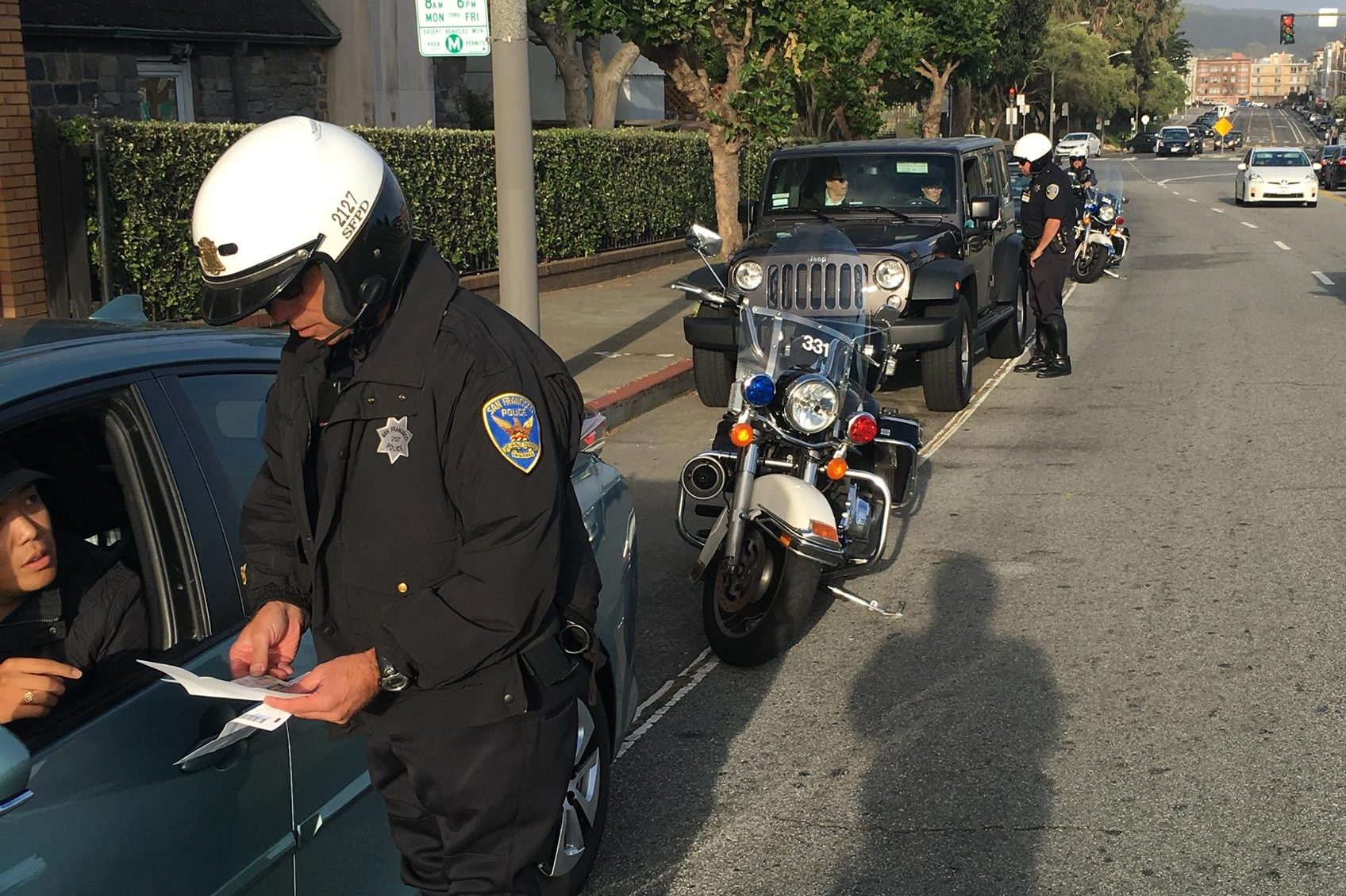 Police officers on motorcycles are conducting a traffic stop on a city street.