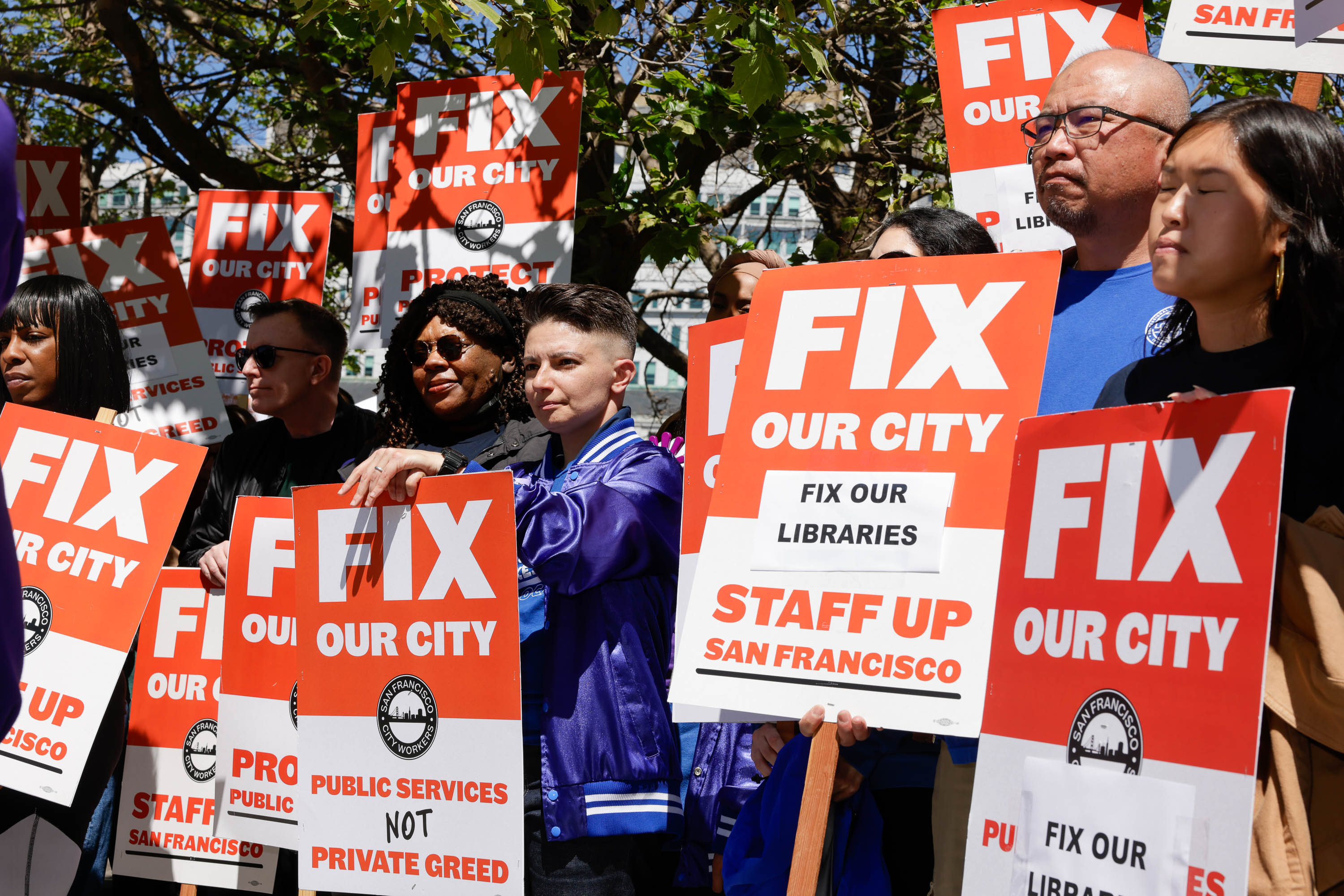 People holding &quot;FIX OUR CITY&quot; signs at a public demonstration.