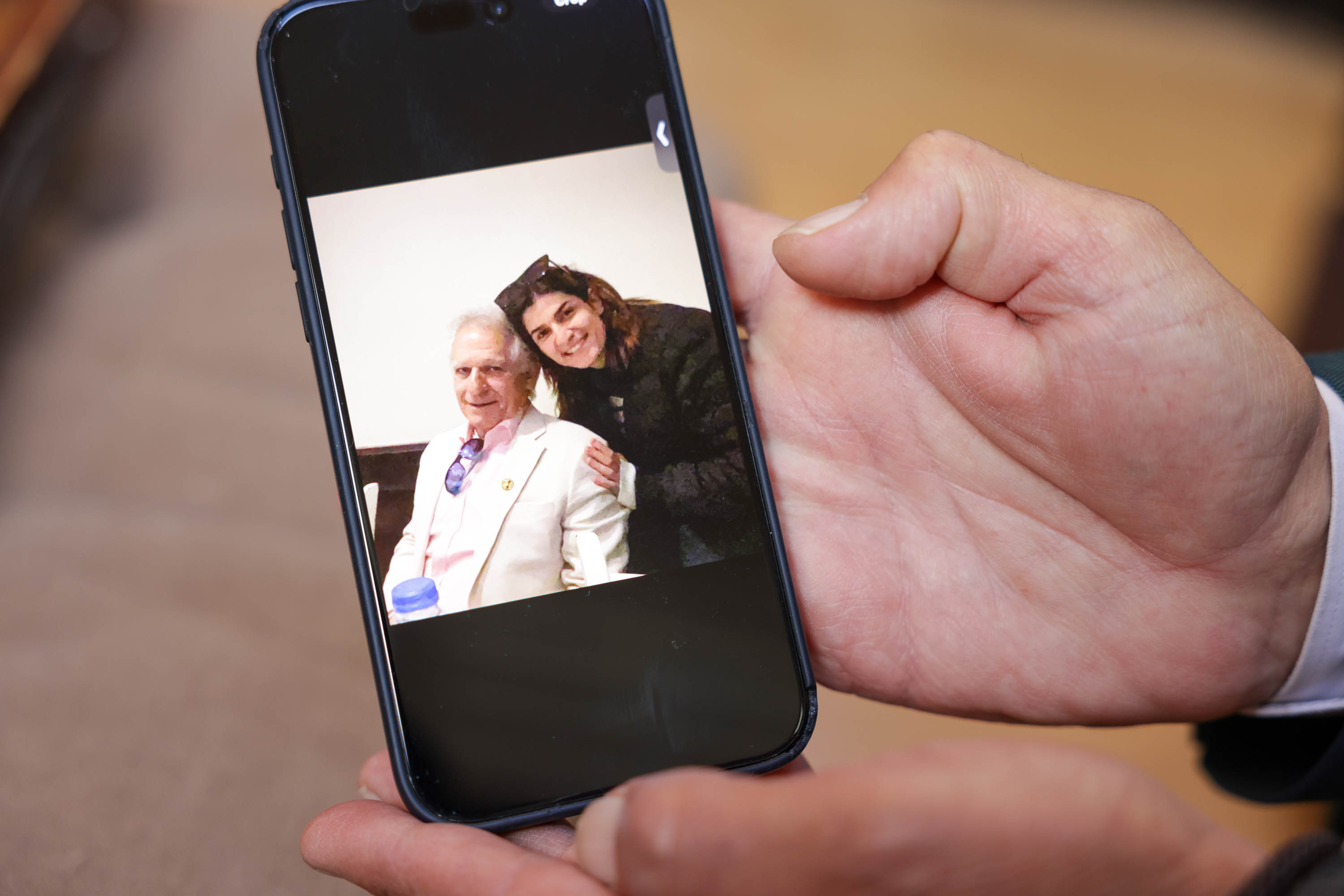 A photo on a phone shows an older person and a younger person smiling together.