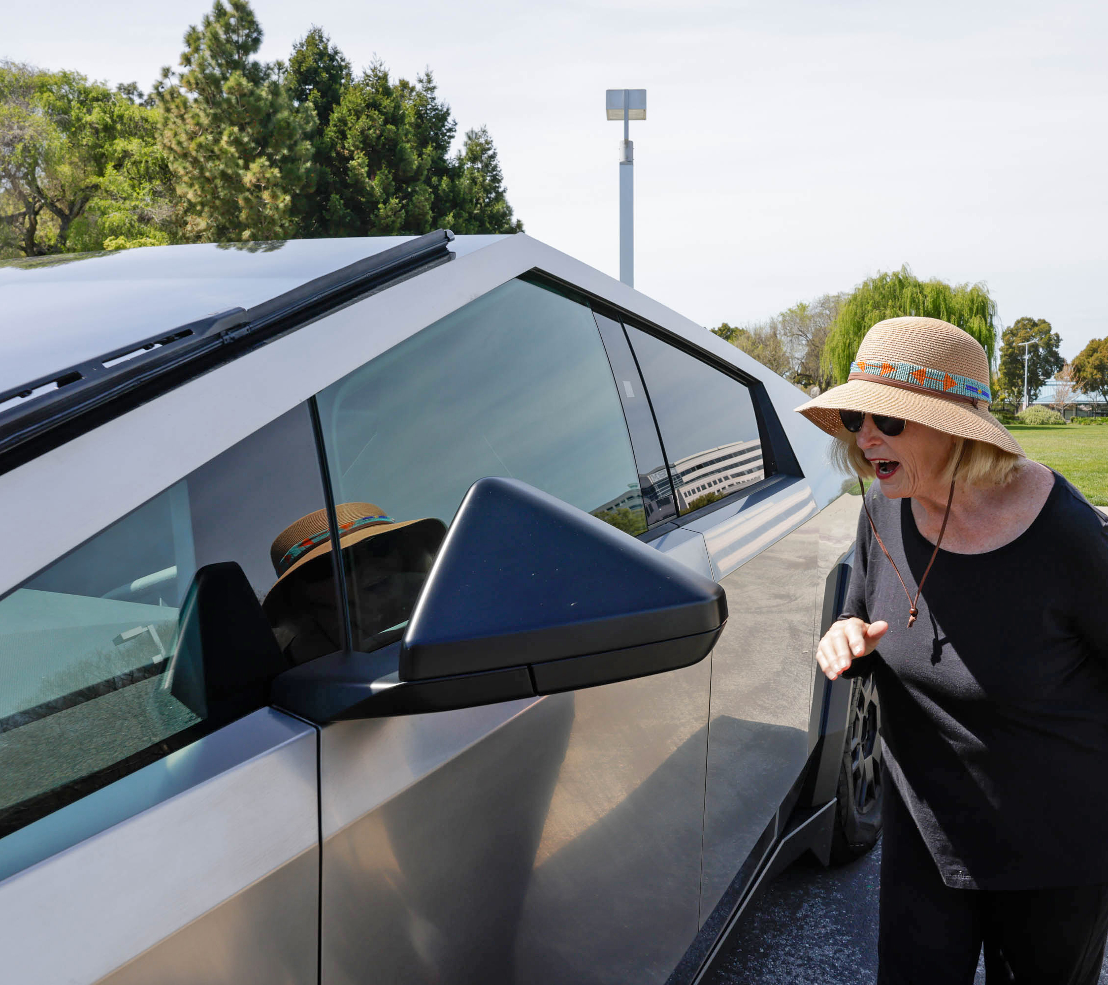 A surprised woman is looking at a futuristic car with an angular design.