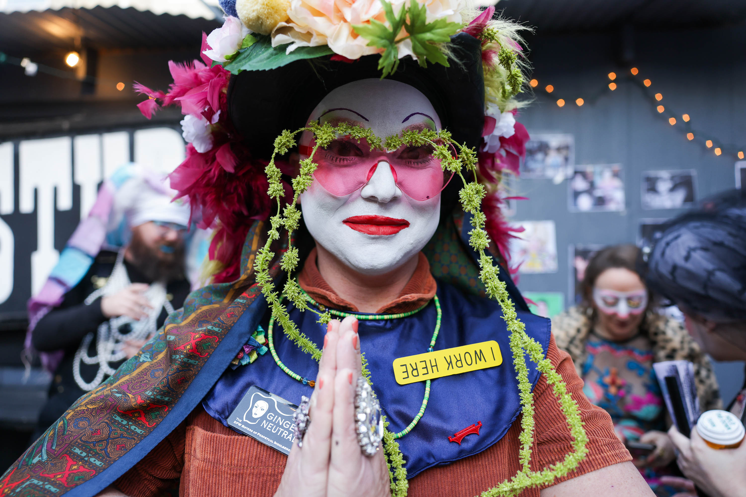 a Sister of Perpetual Indulgence nun in a flowery had, pink sunglasses and whiteface makeup