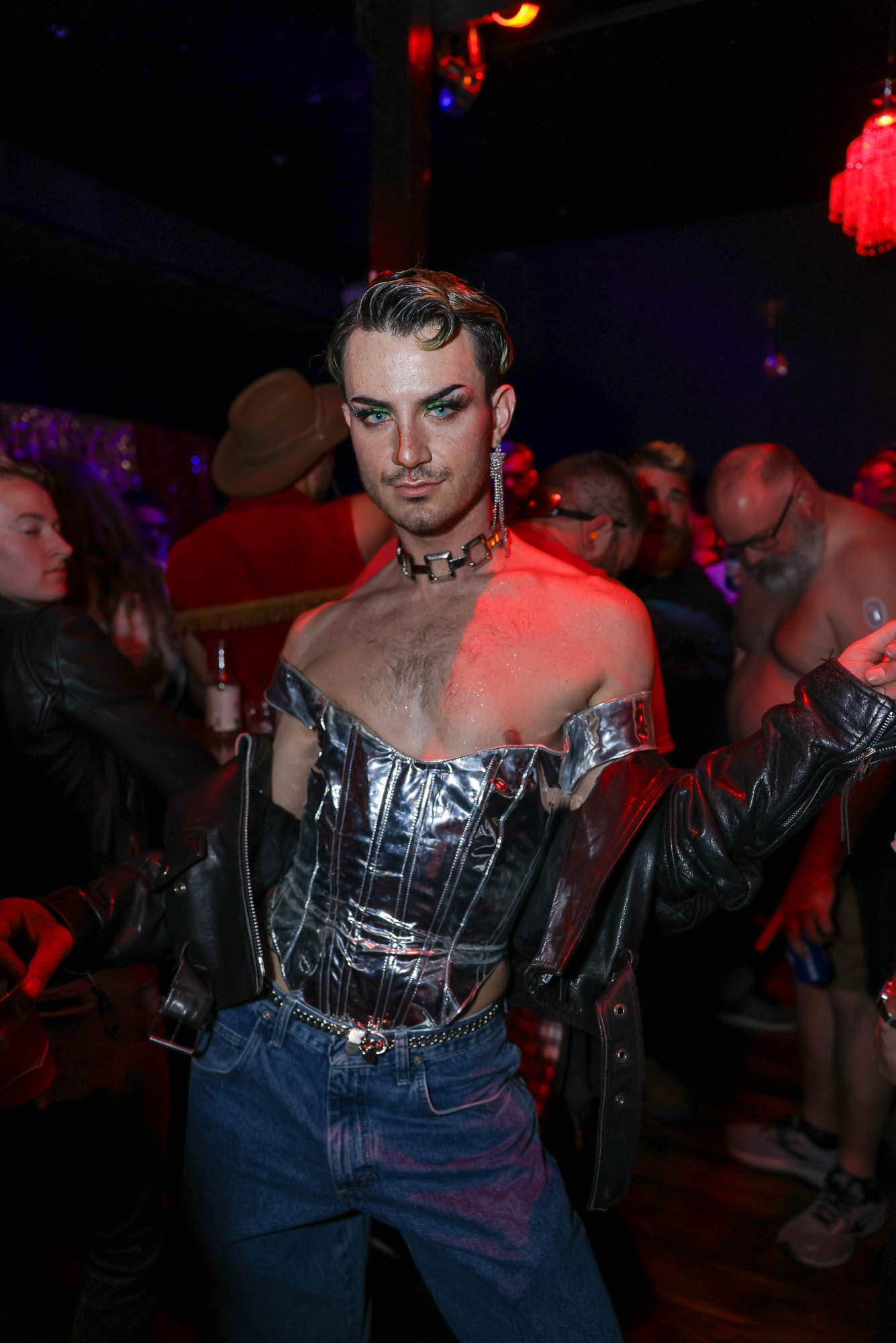 a drag performer in a silver sequin top and bare shoulders smolders on a dance floor