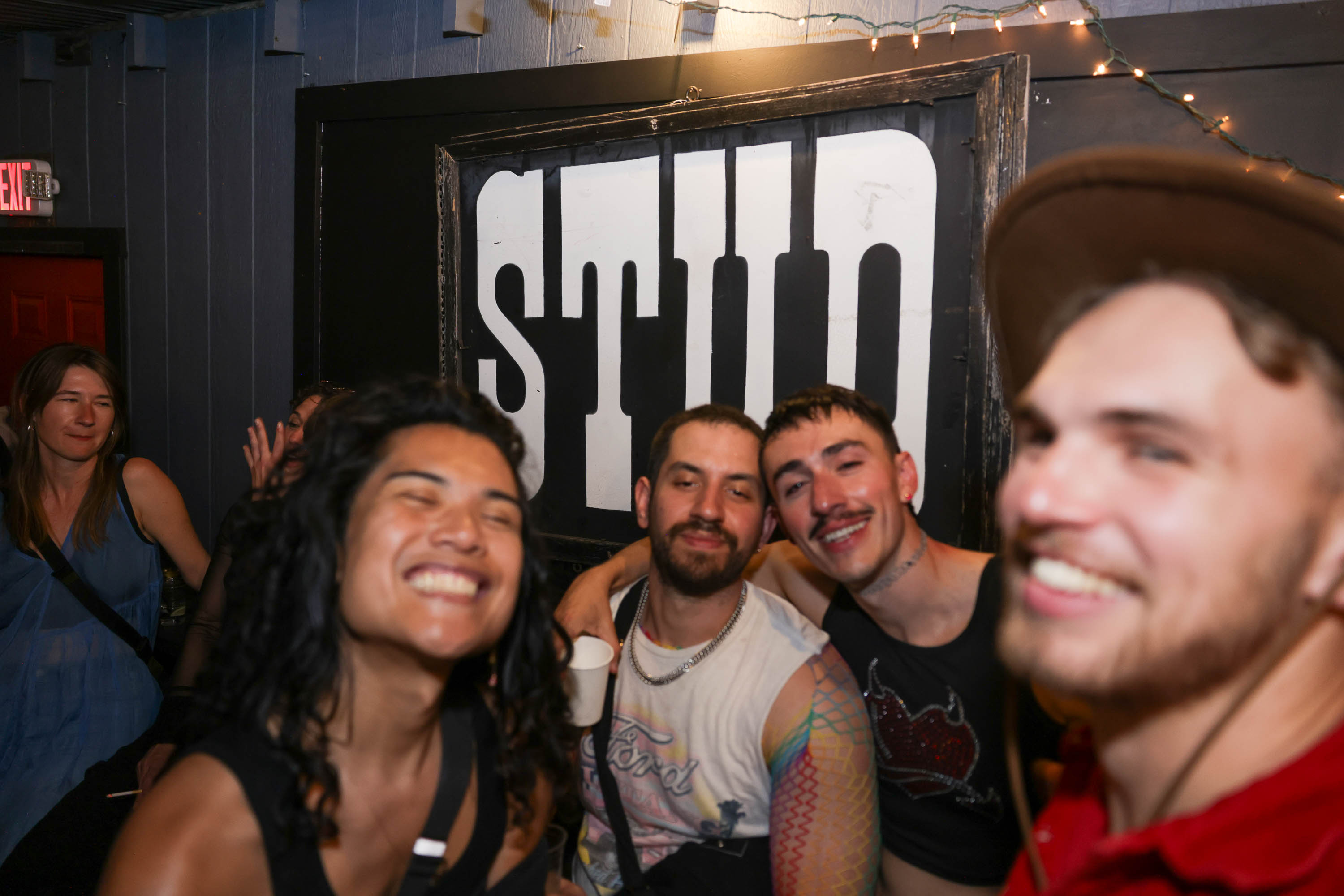 a group of friends smile in front of The Stud sign