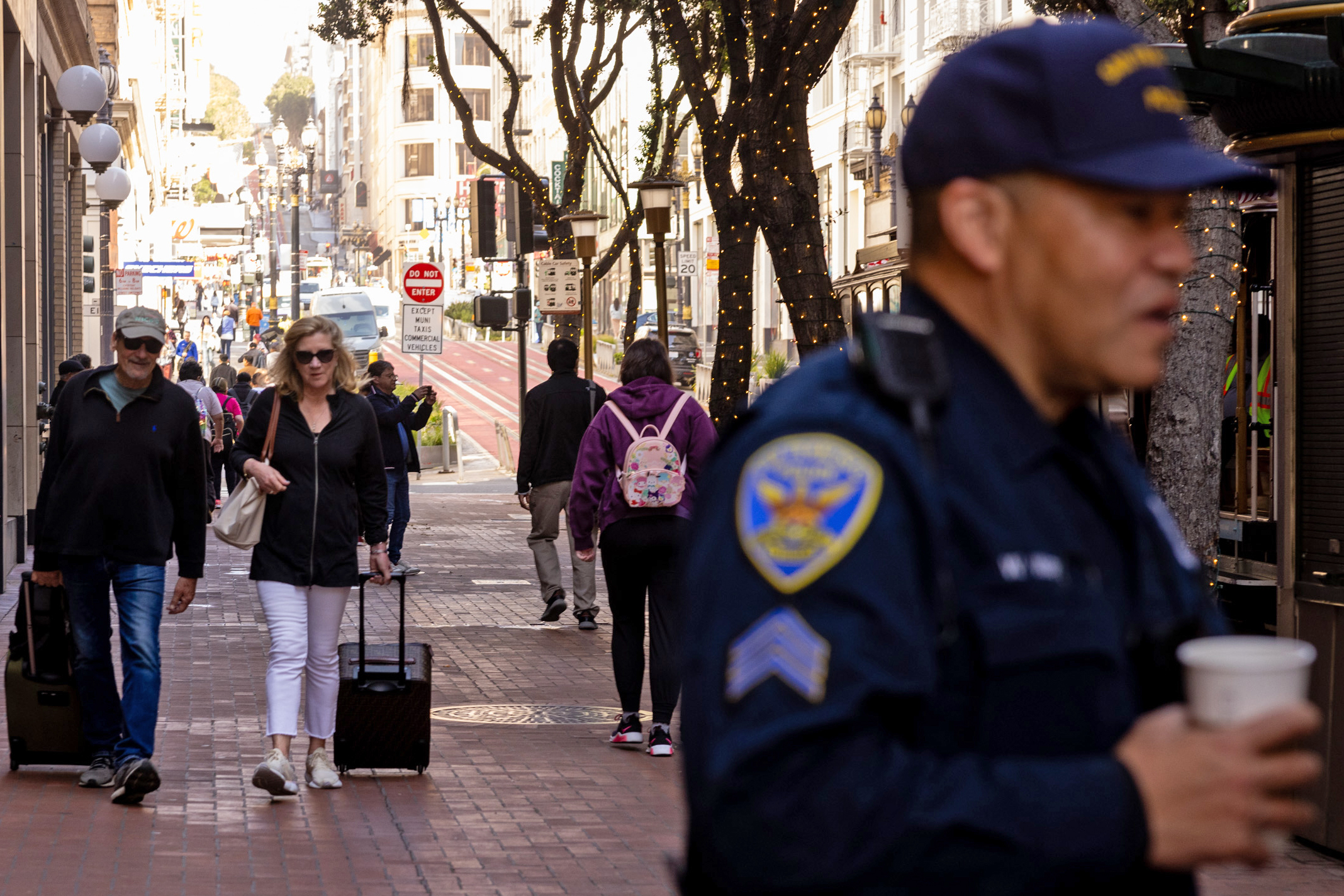 A busy city street with pedestrians and a police officer in the foreground.