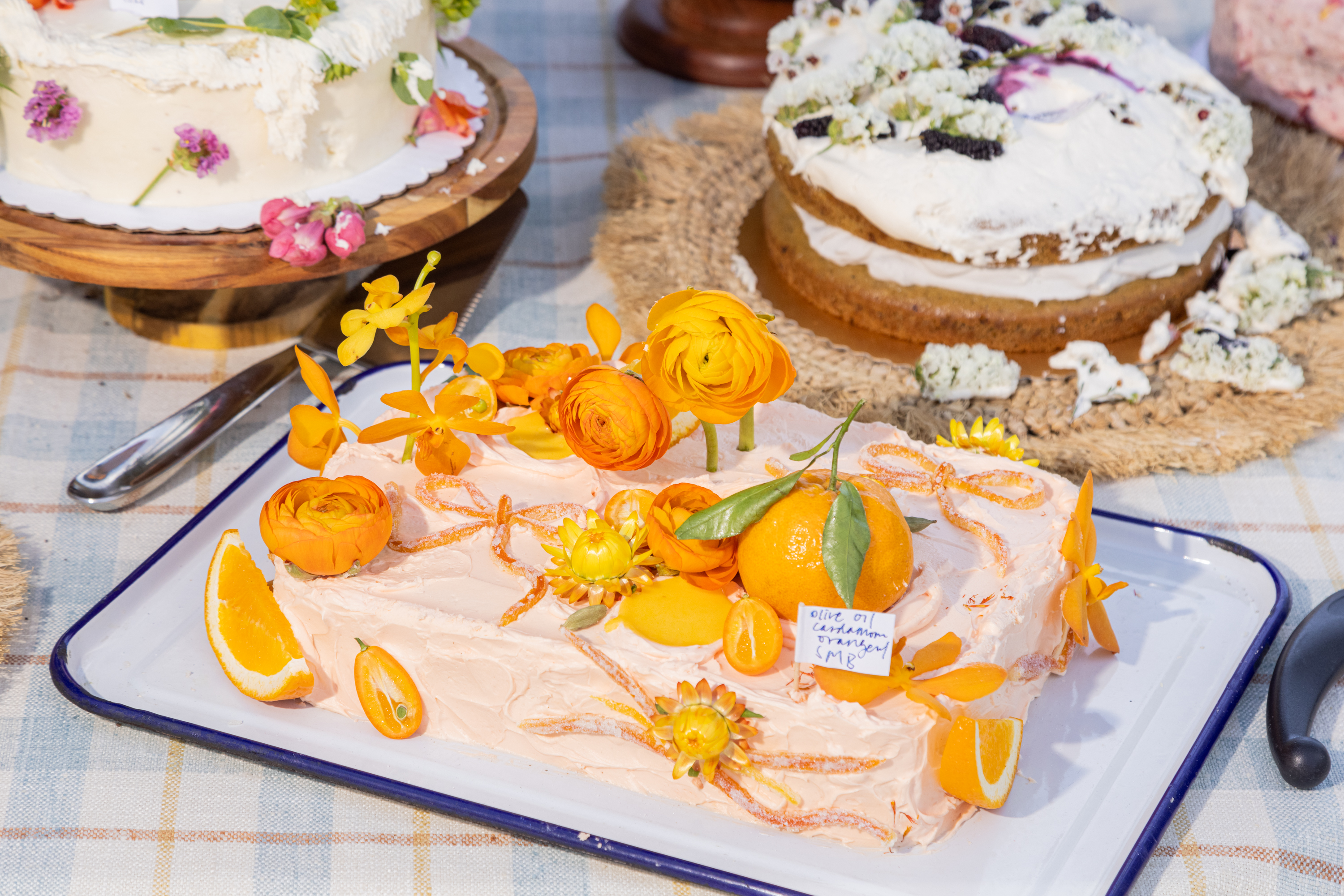 A table with decorated cakes adorned with vibrant orange flowers and citrus slices.