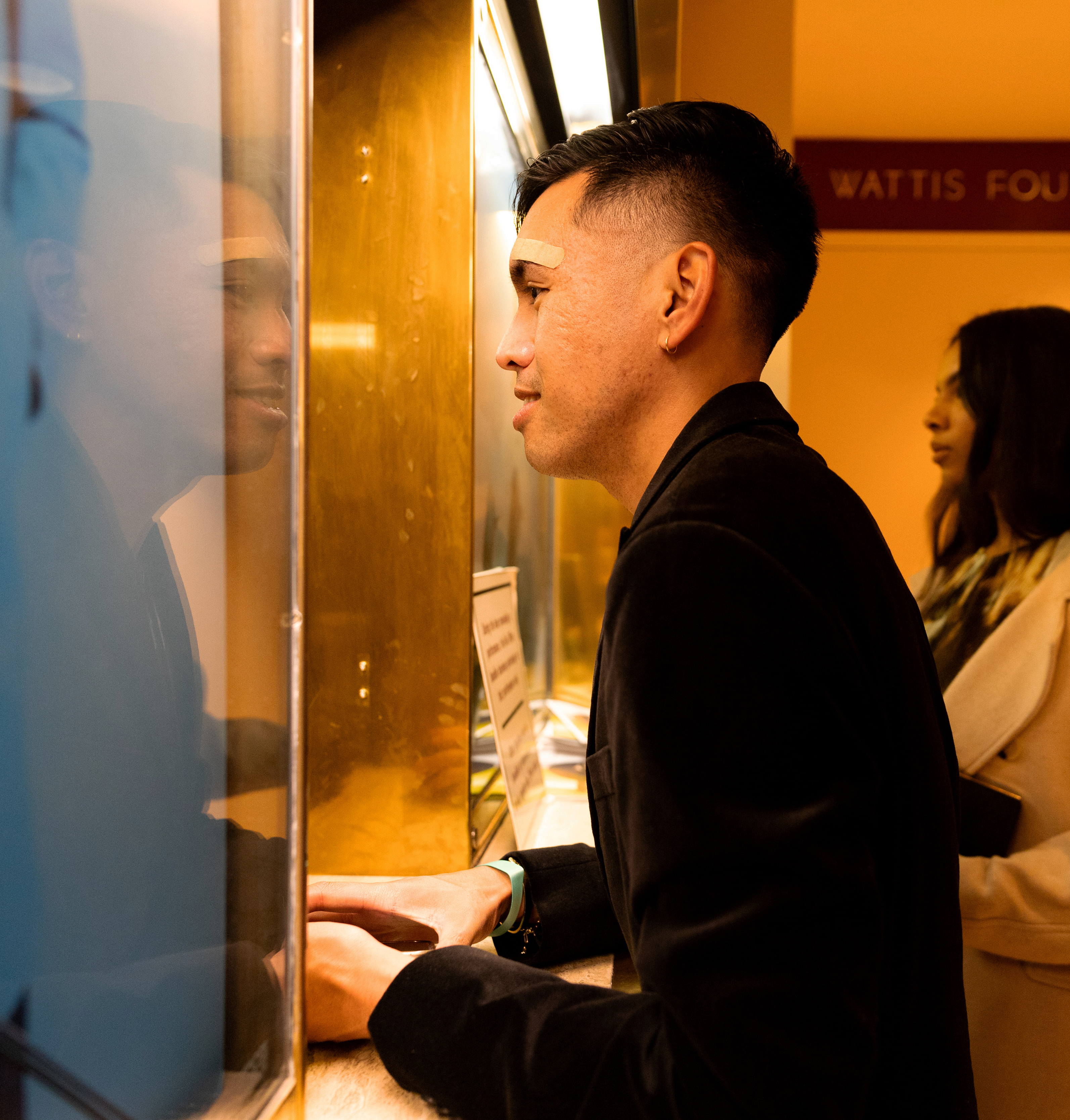 A man in a black jacket peers into a display case with interest, a woman visible behind him.