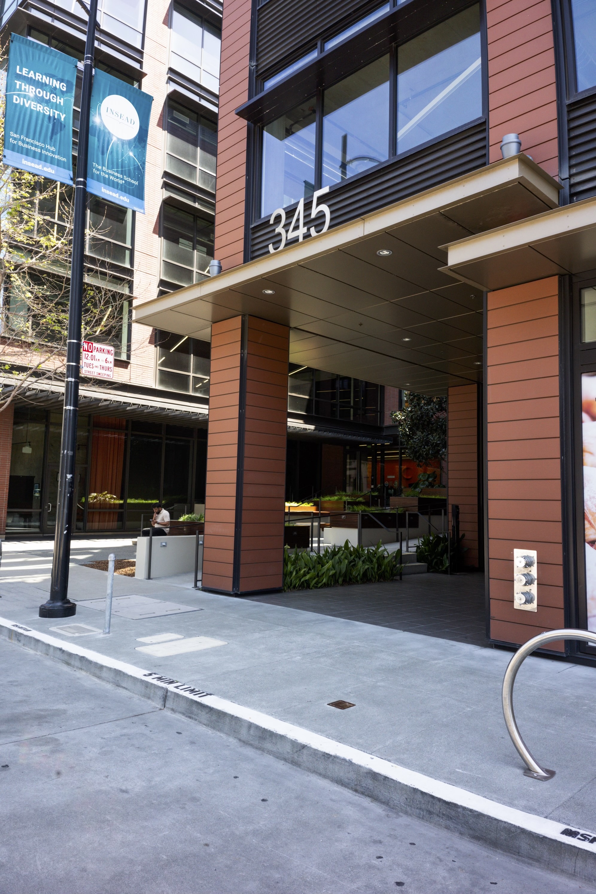 An urban building entrance with a large &quot;345&quot; sign, a banner, a no parking sign, and a bike rack.