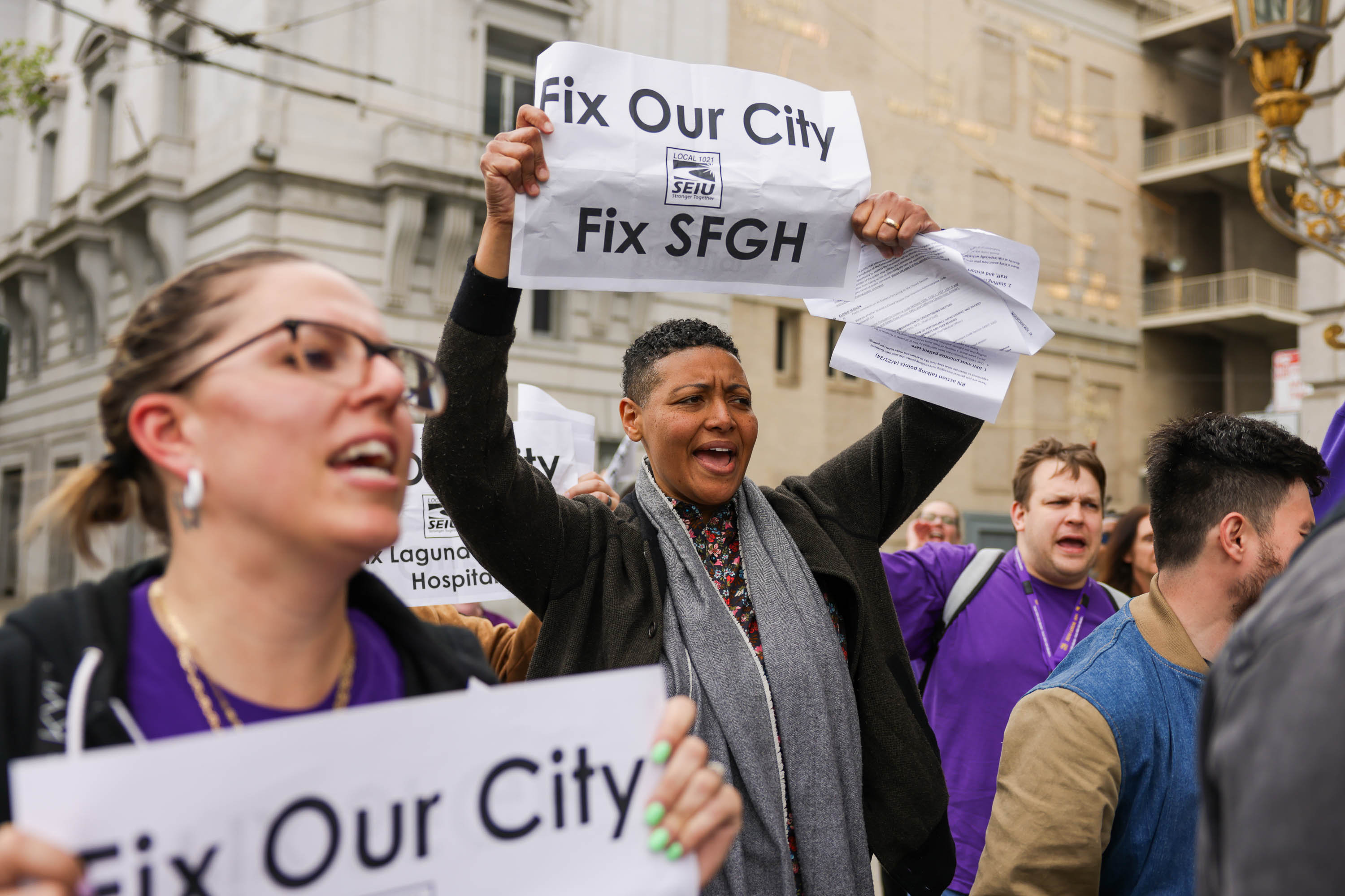 People are protesting with signs that read "Fix Our City" and "Fix SFGH," showing strong emotions.