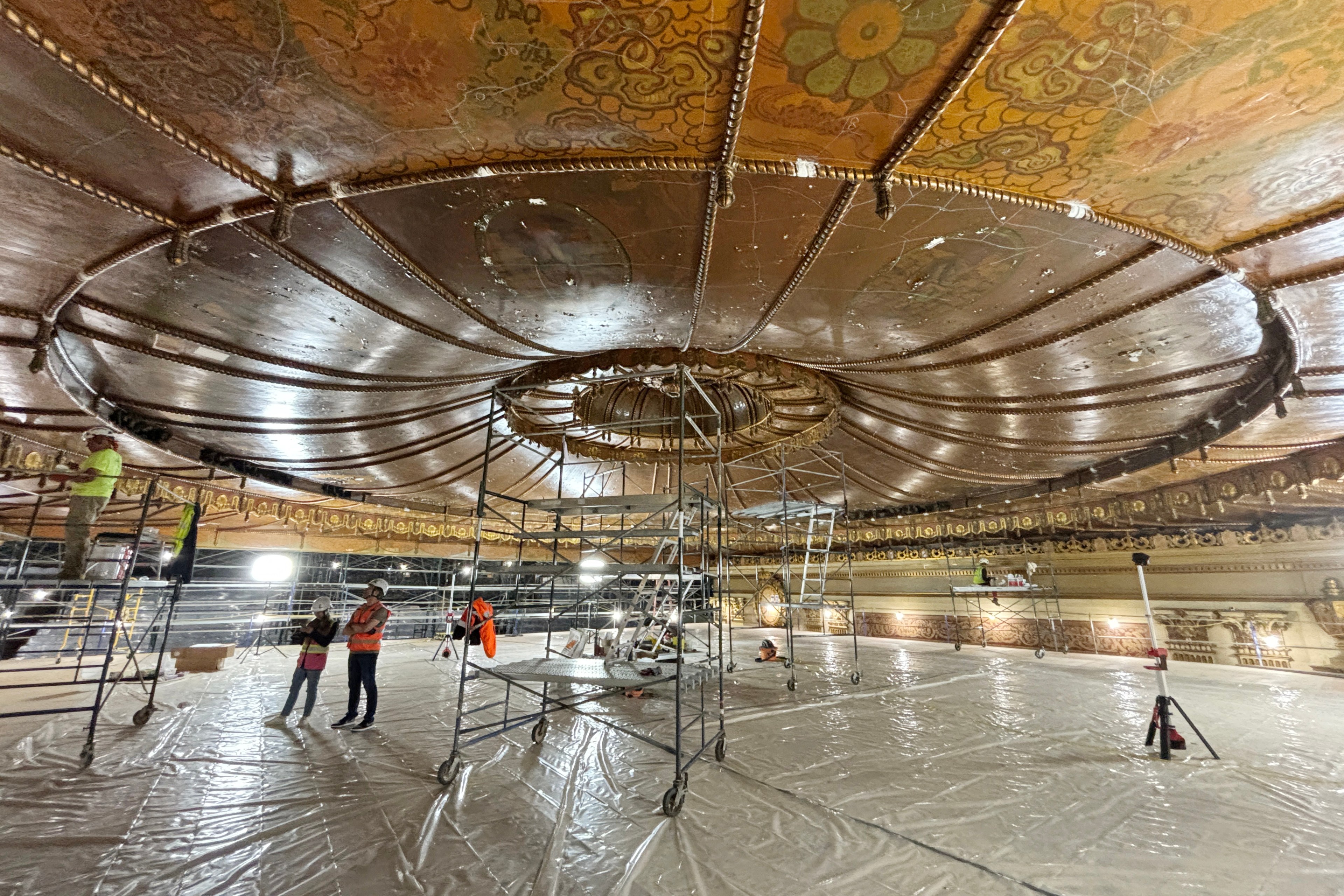 a zoomed-out image of a platform in the Castro Theatre showing people at work and the ceiling where the chandelier will go once it's restored.