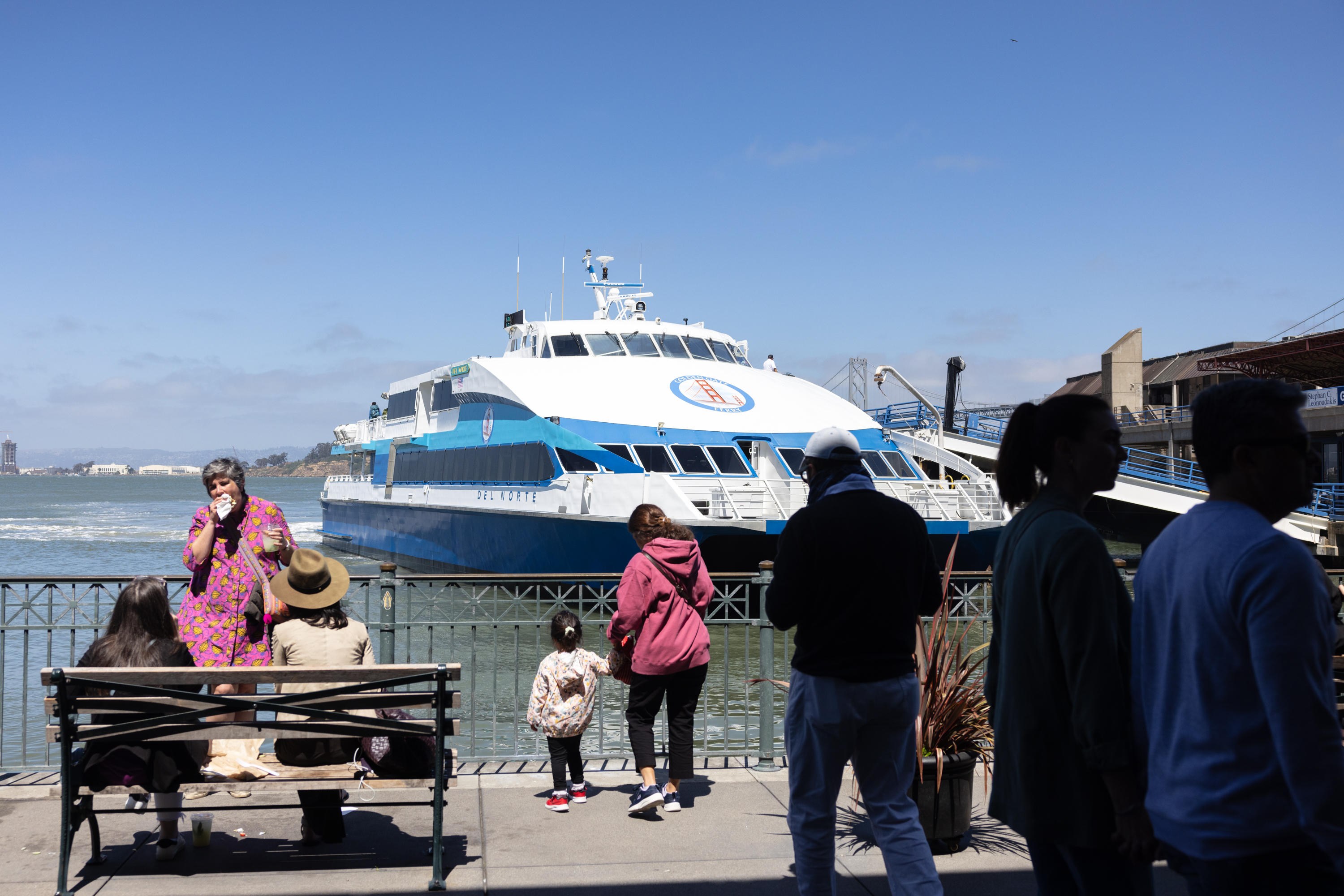 People on a dock observe a ferry boat on the water.