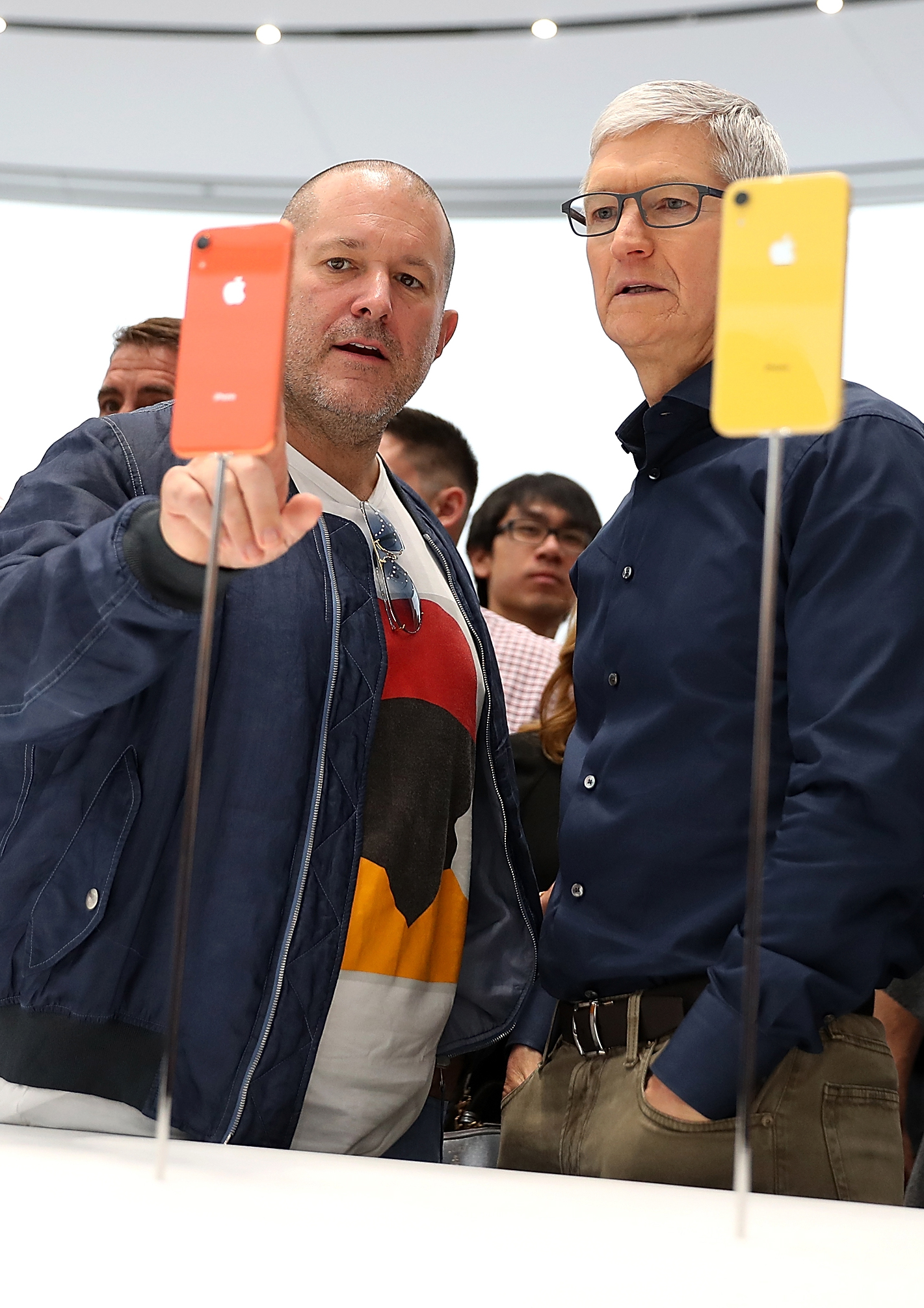 Two men holding up colorful smartphones in a brightly lit, modern space.