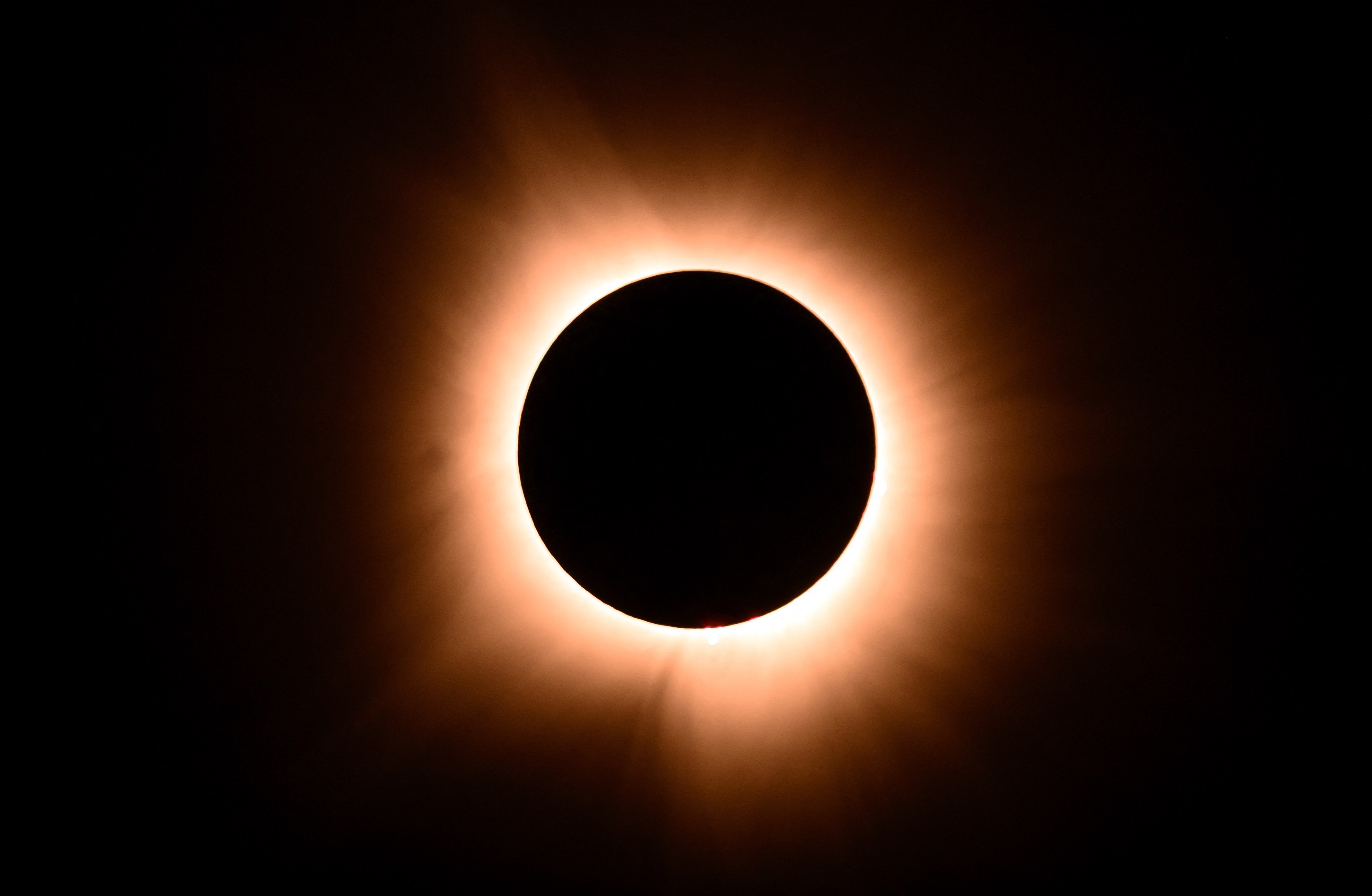 A solar eclipse with a bright corona surrounding the dark moon silhouette against a black sky.