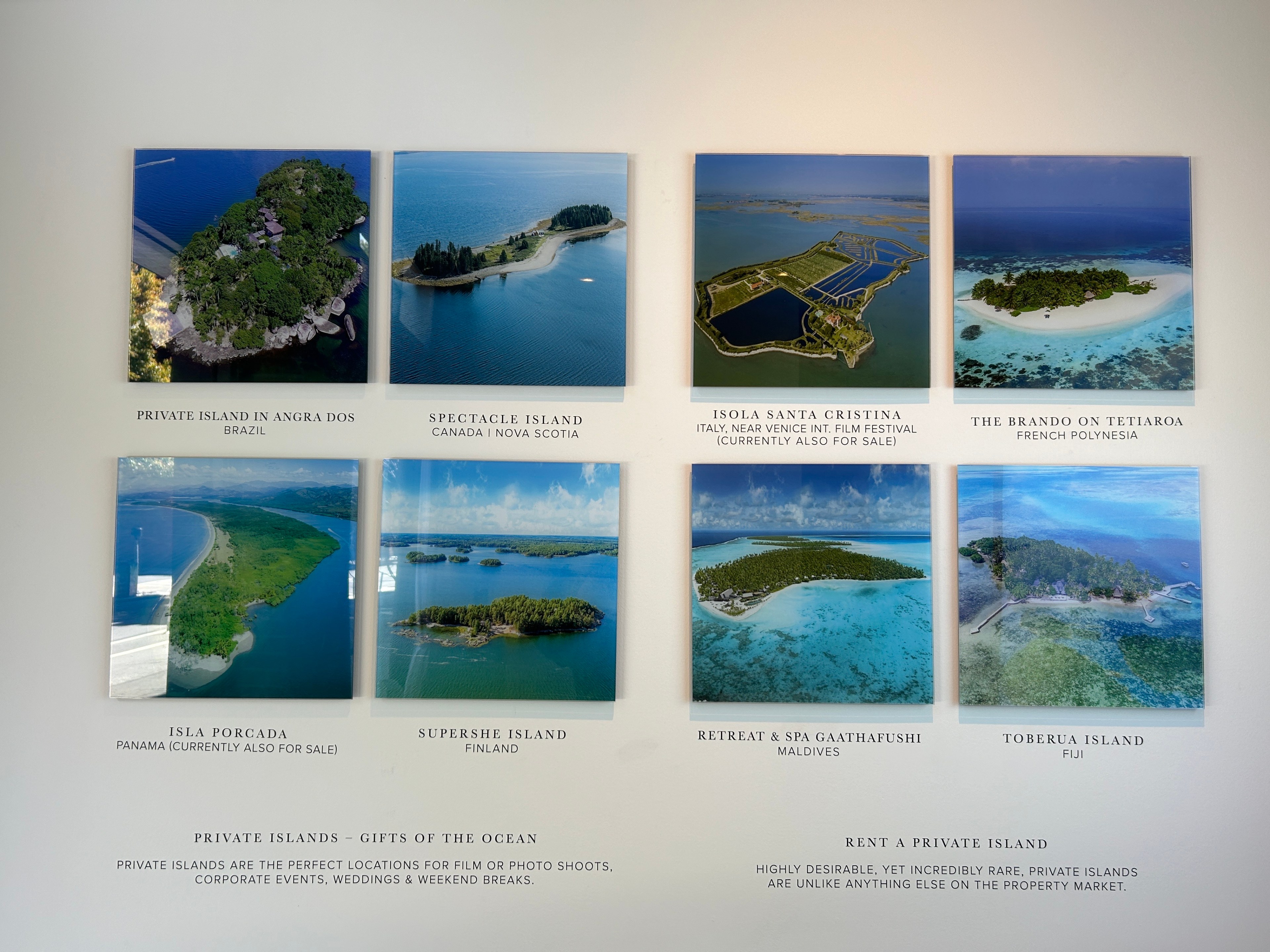 gallery-style, wall-mounted displays of available island properties showing eight tropical locations