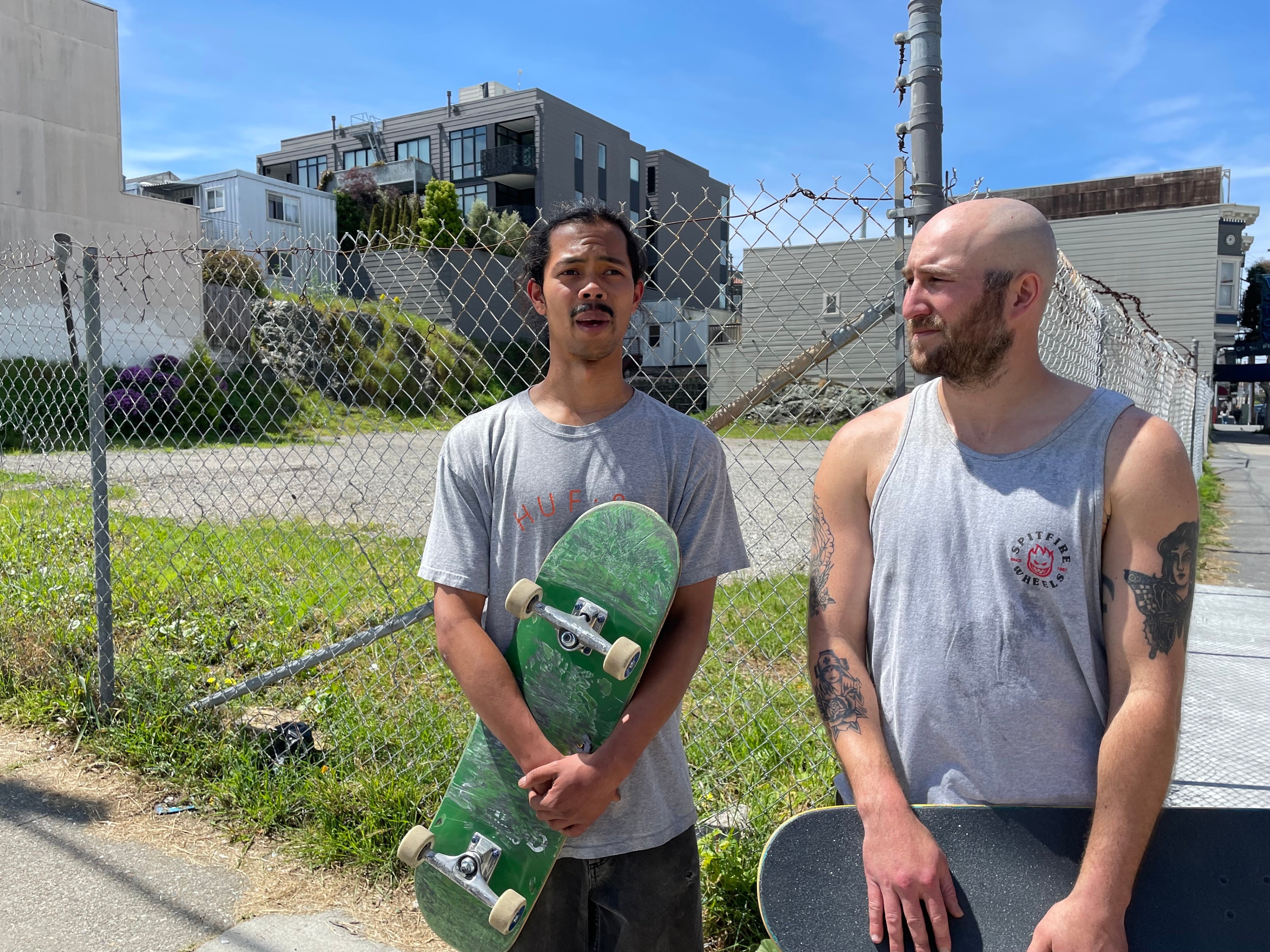 Two men stand holding skateboards in a photo.