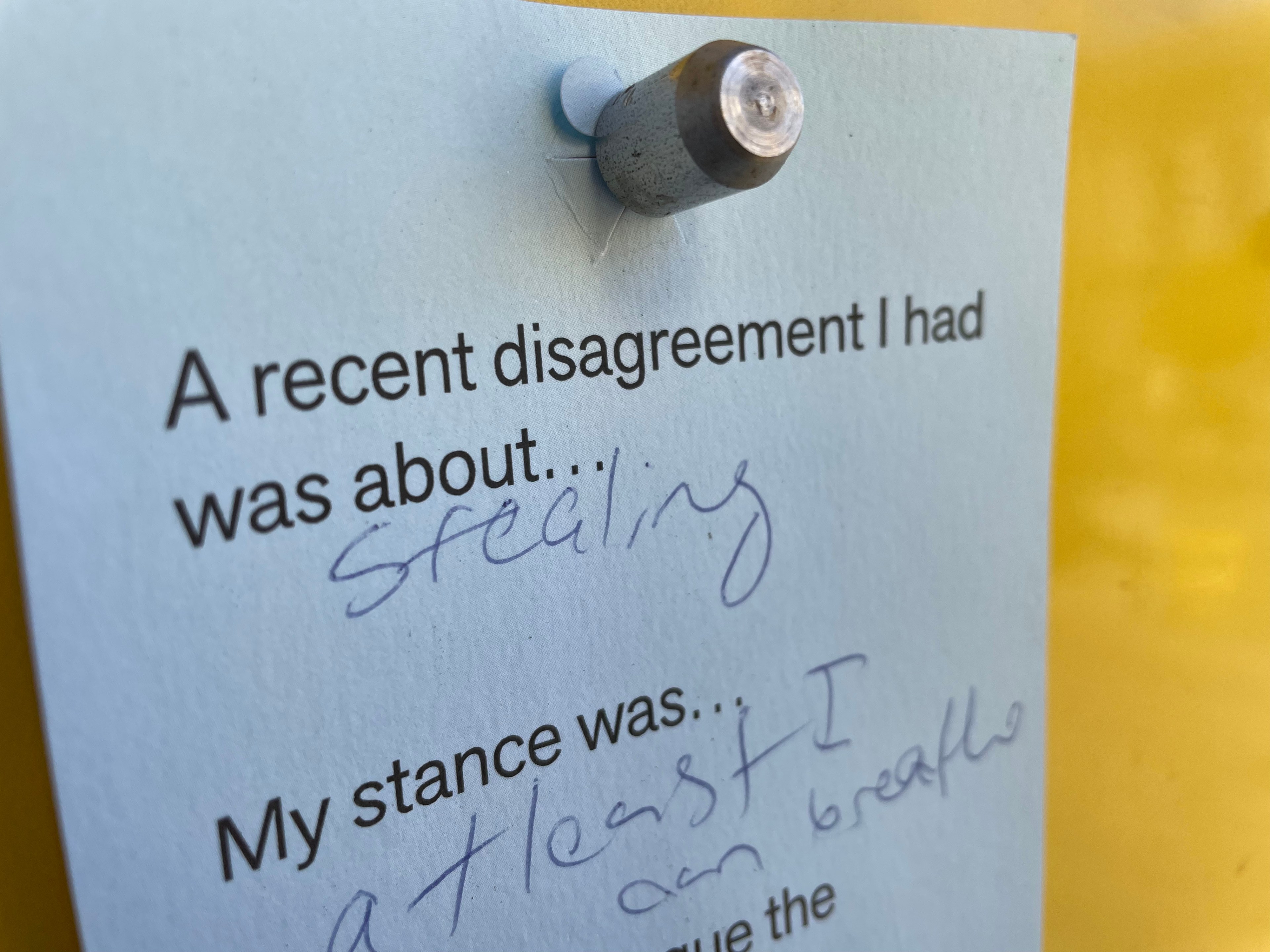 A note pinned to a yellow background reads, "A recent disagreement I had was about stealing. My stance was... least I can breathe" with words blurred.