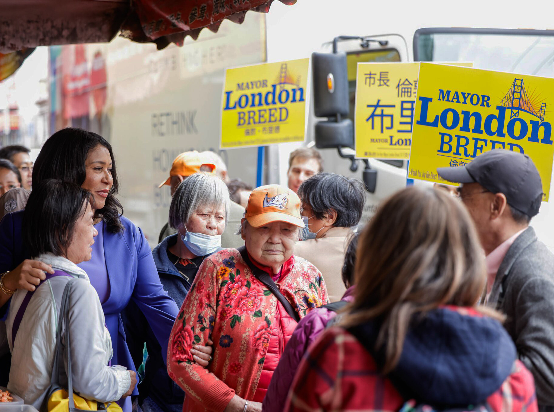 A group of seniors with &quot;Mayor London Breed&quot; signs in a bustling, lively setting.