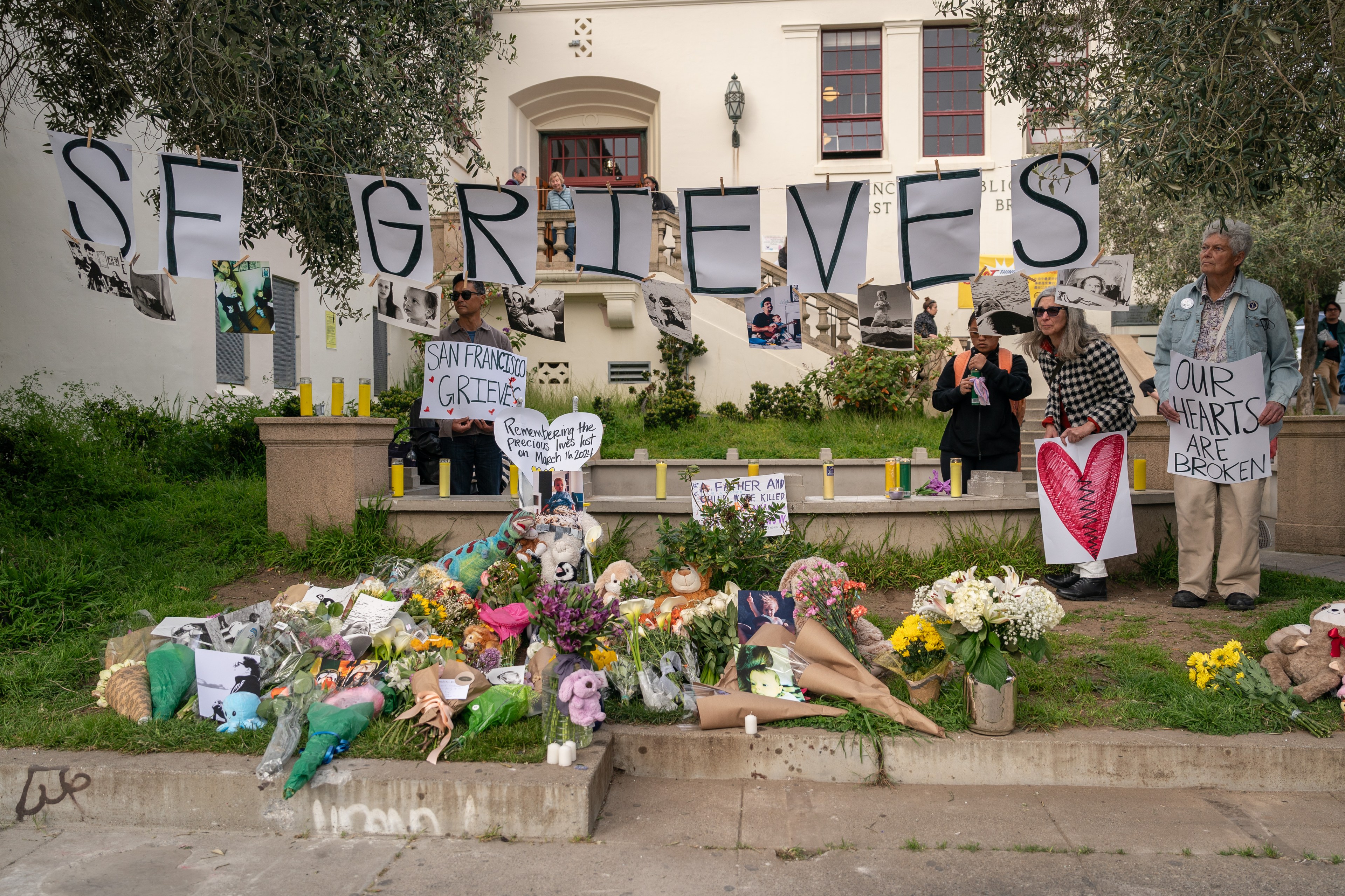 A vigil with flowers, candles, signs saying &quot;SAN FRANCISCO GRIEVES&quot; and &quot;OUR HEARTS ARE BROKEN,&quot; in front of a building.