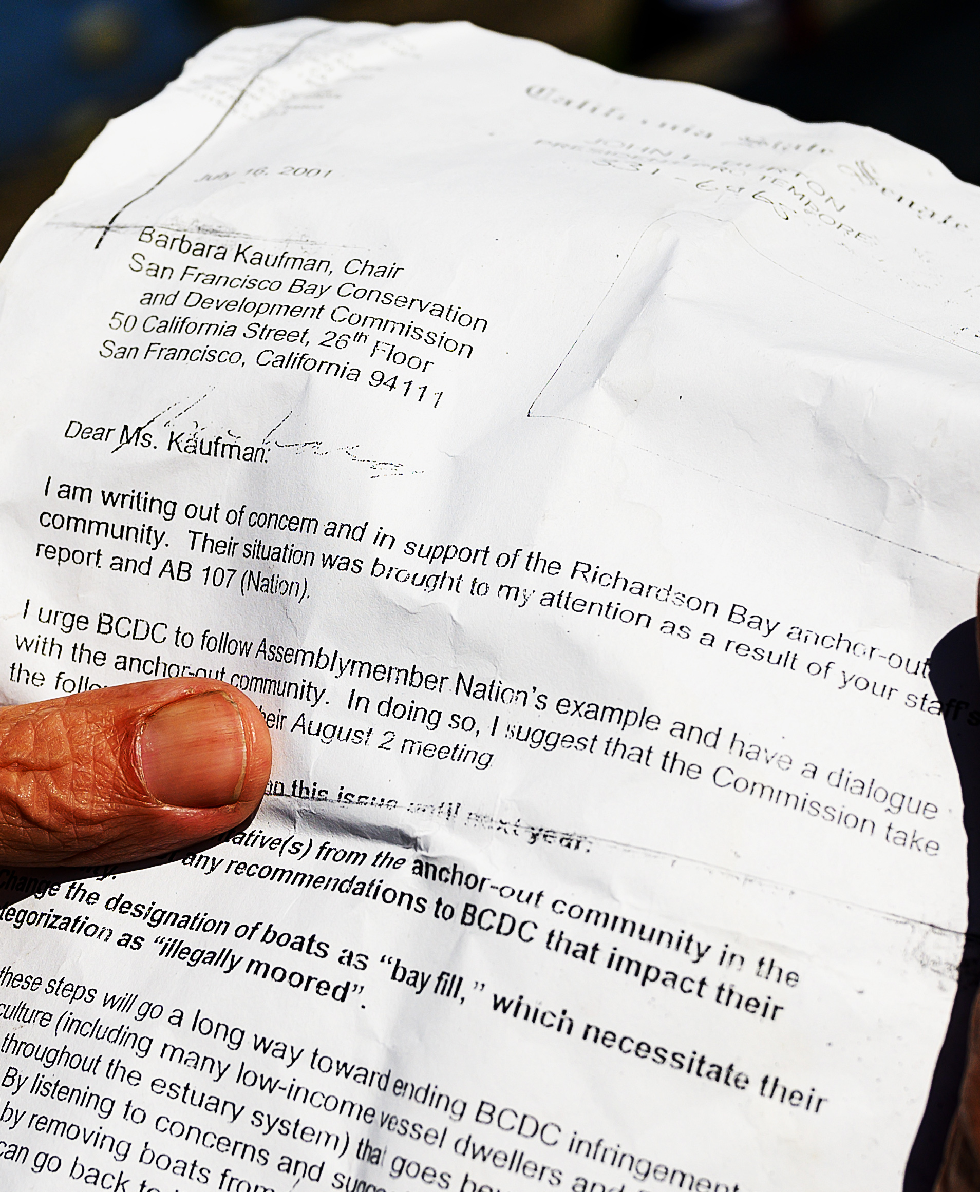 A wrinkled letter is held by a hand, addressed to Barbara Kaufman regarding concerns for the Richardson Bay anchor-out community.