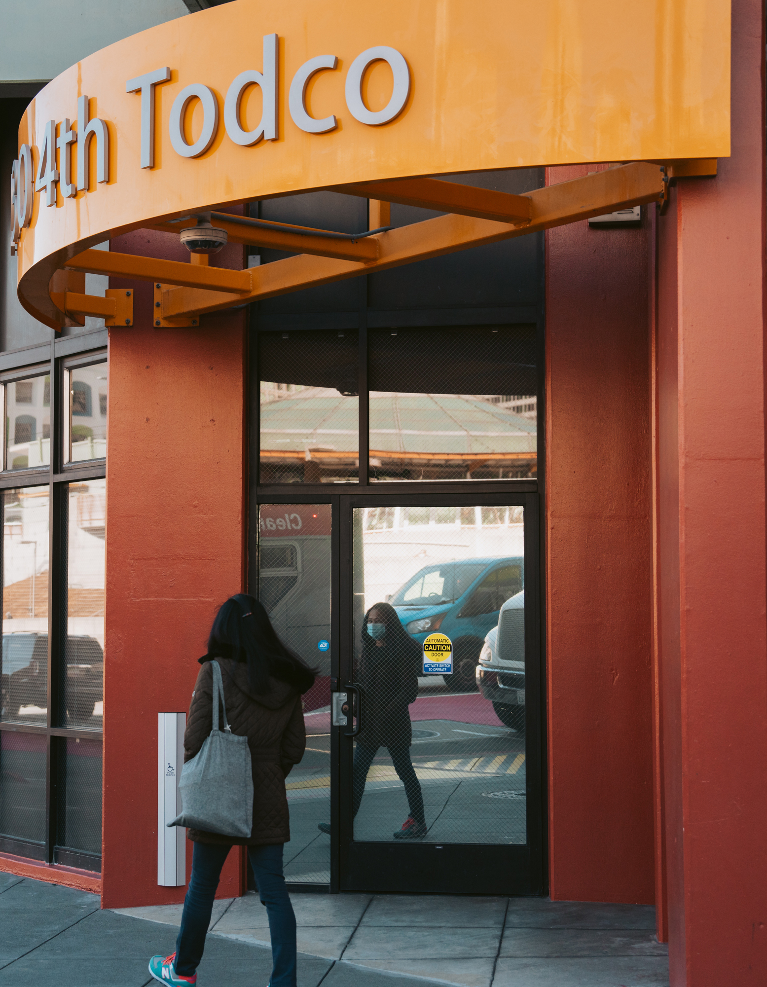 A person walks by a building entrance with a &quot;TODCO&quot; sign above the door.