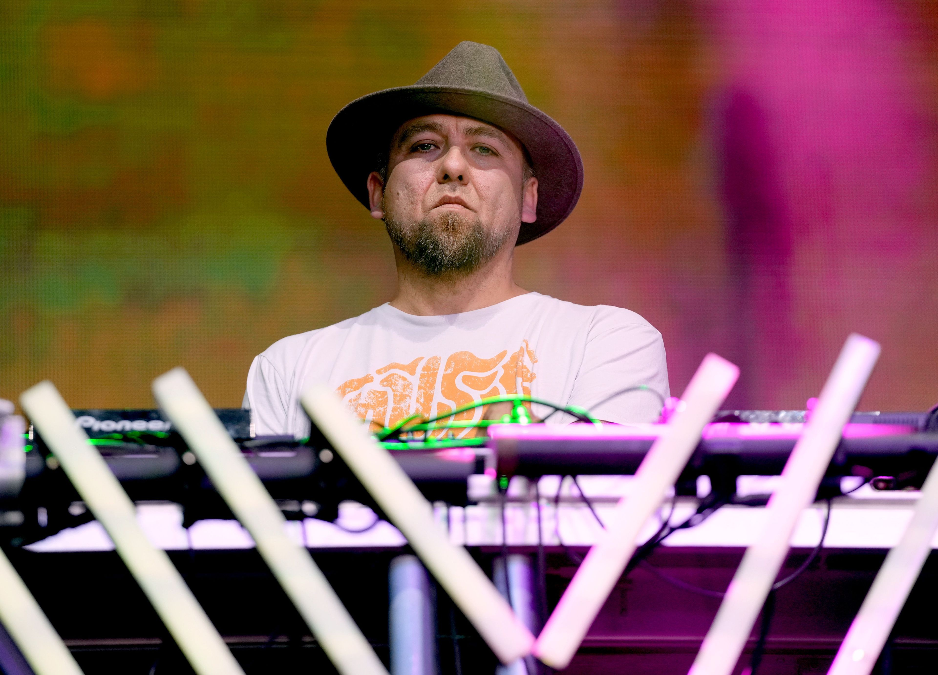 a goateed whit man in a brimmed hat wears a serious expression as he DJs