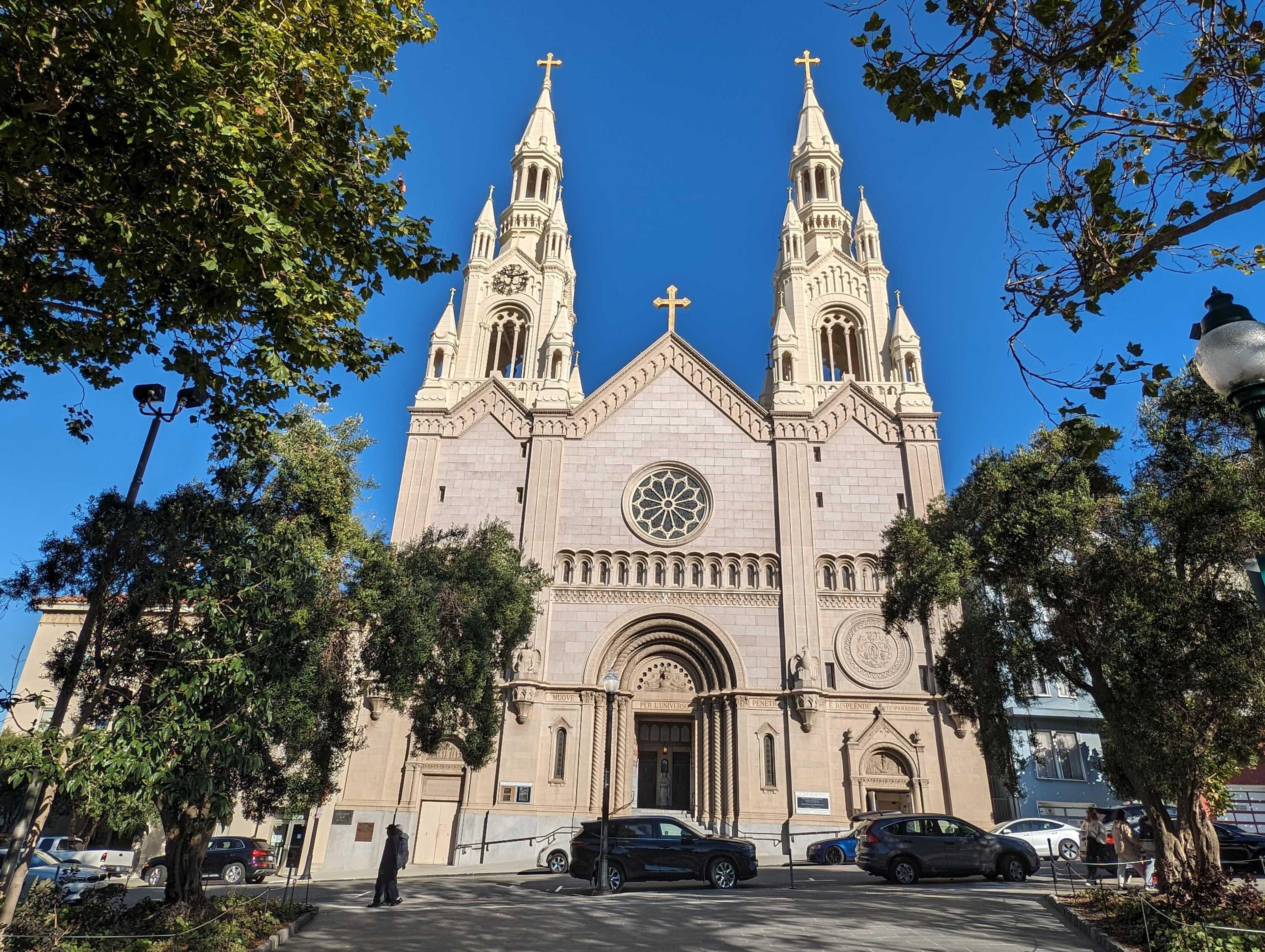 A Catholic church stands above a quiet city street on a sunny day.
