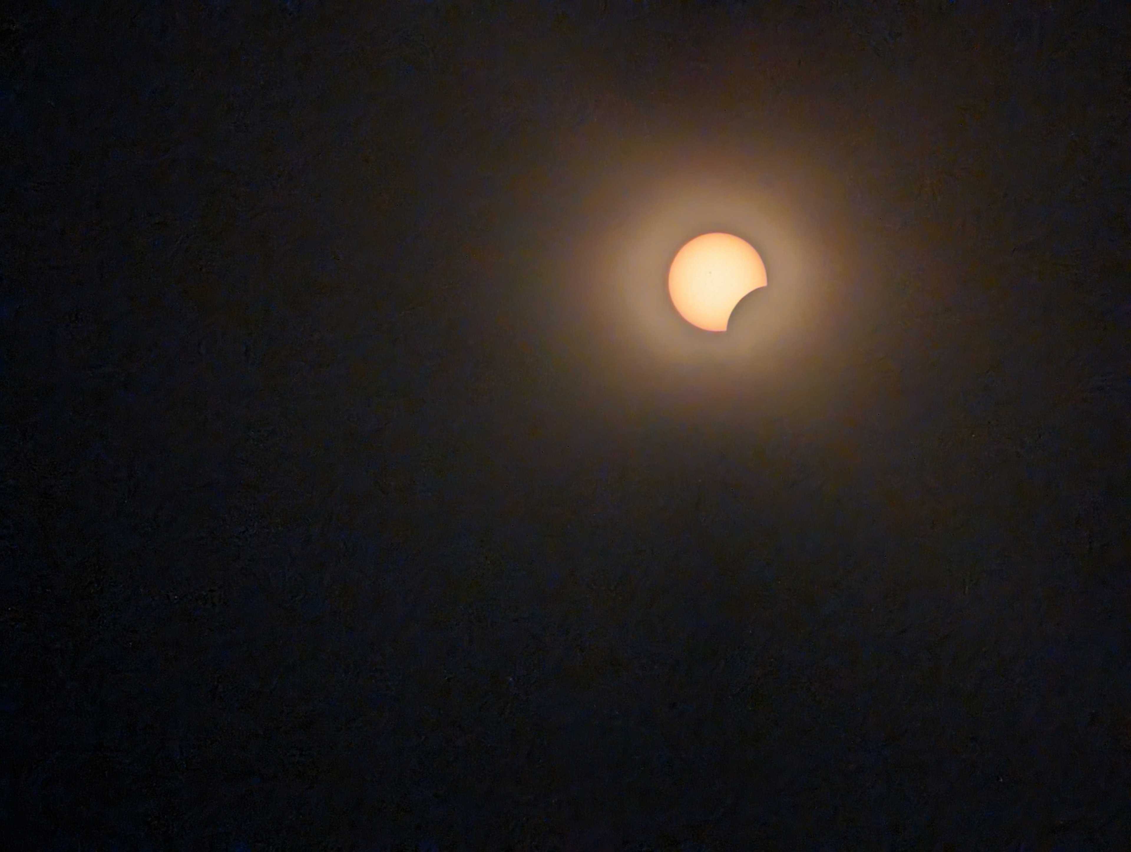A solar eclipse with the sun partially obscured by the moon, against a dark sky.