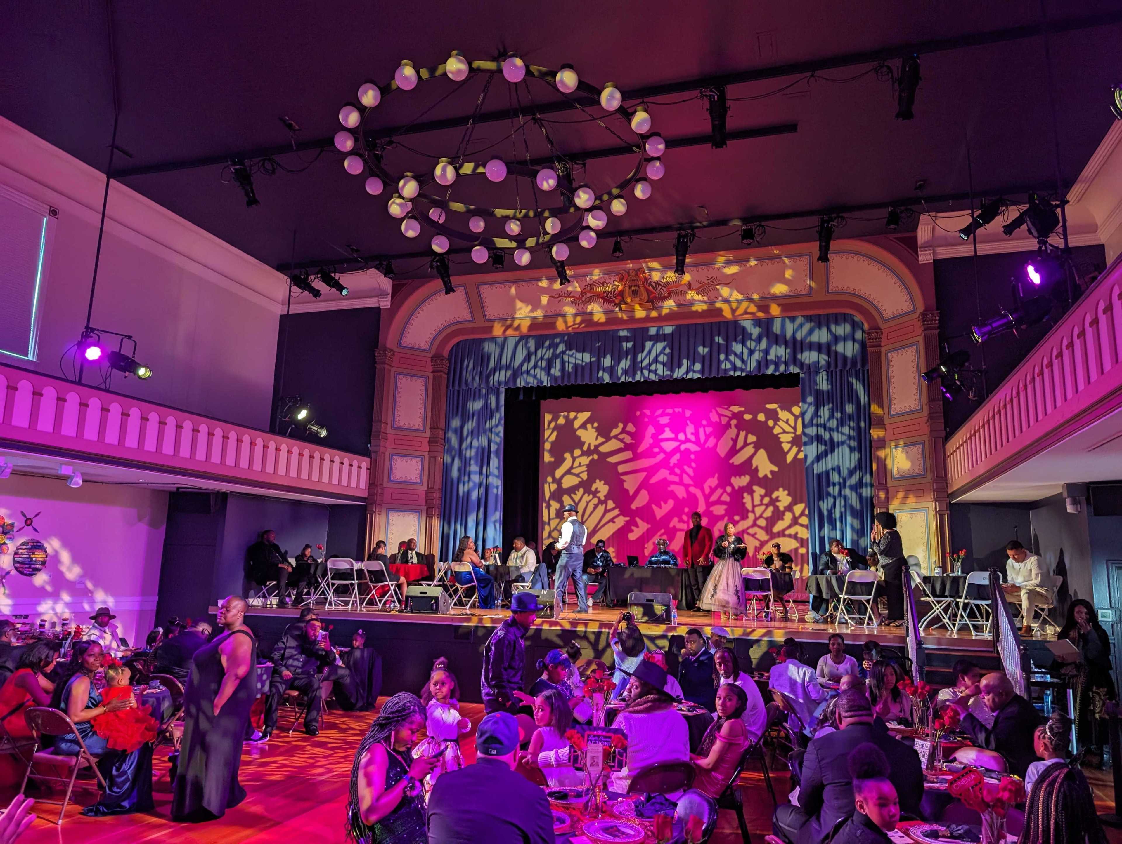Tables fill a theater under hanging lights at the start of a father-daughter dance.