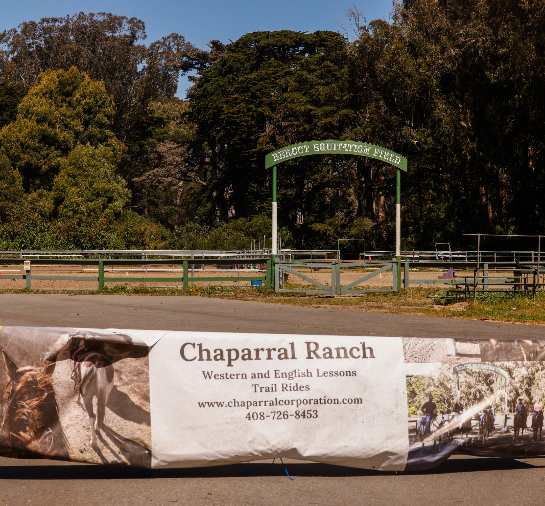 The image shows an arch labeled &quot;Bercut Equitation Field&quot; at the entrance to an equine field framed by trees, and a weathered banner for &quot;Chaparral Ranch&quot; in the foreground.