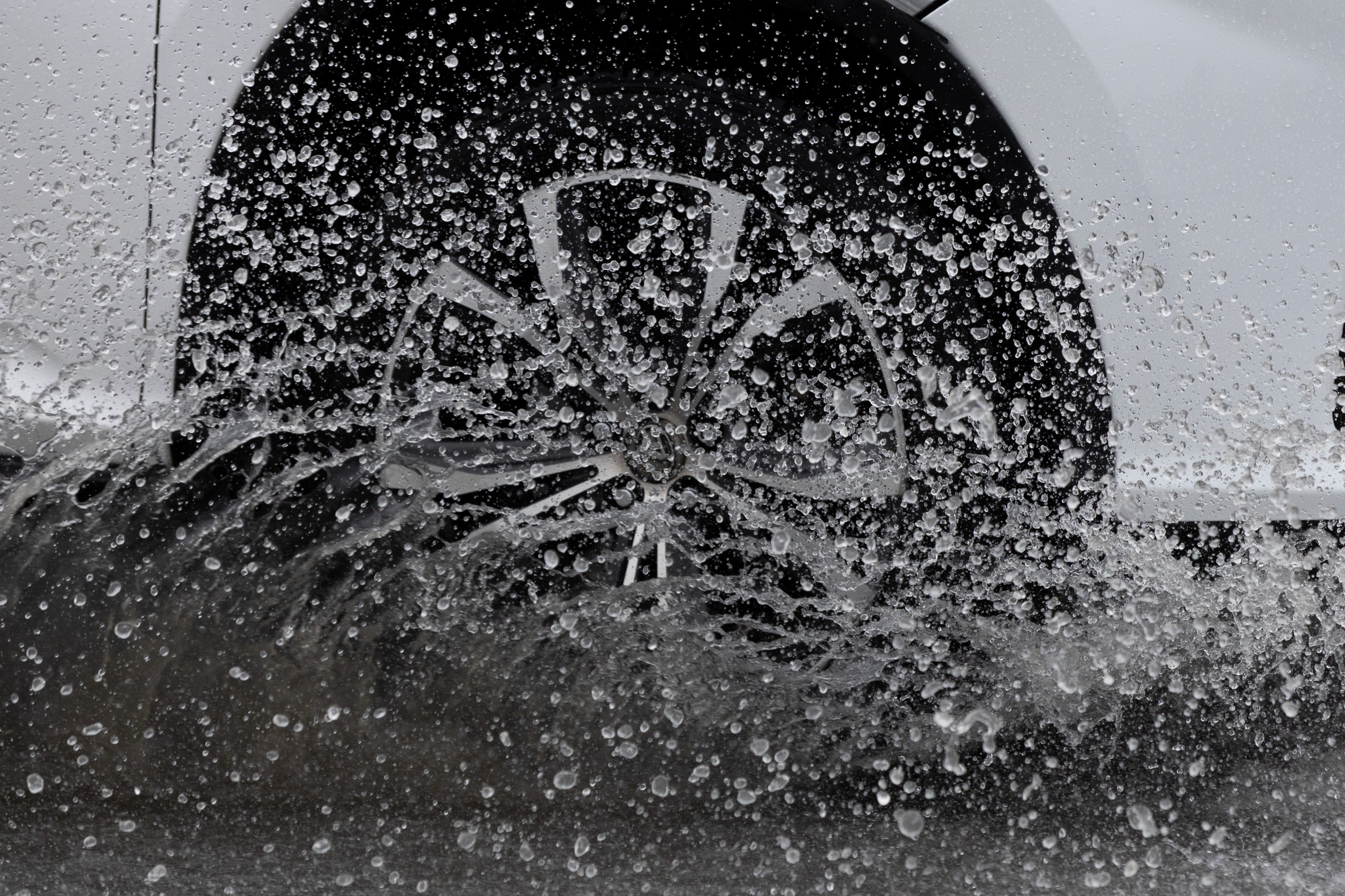 A car wheel is splashing through water, droplets frozen in motion.