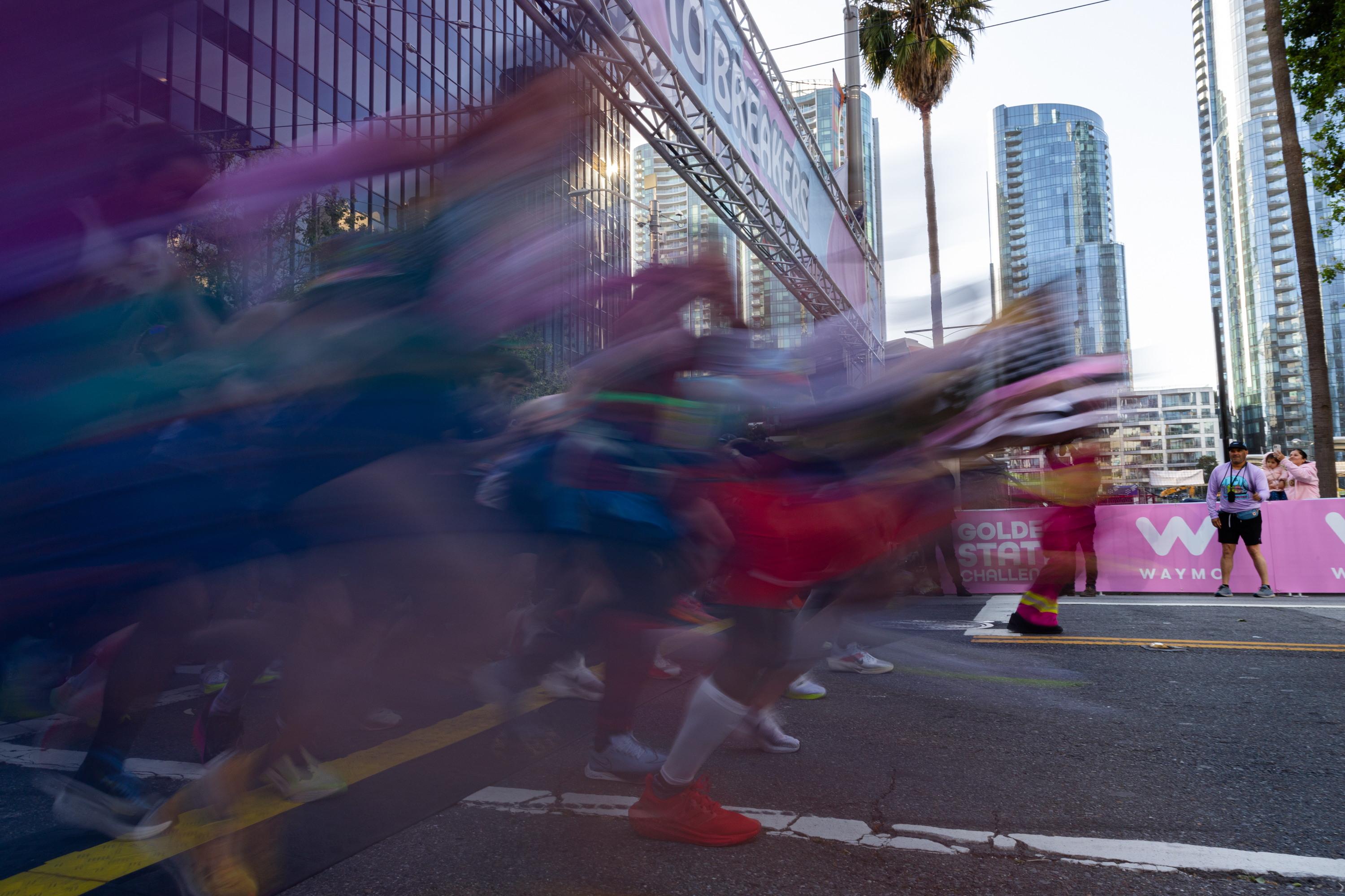Colorfully costumed runners leave a starting line in time lapse