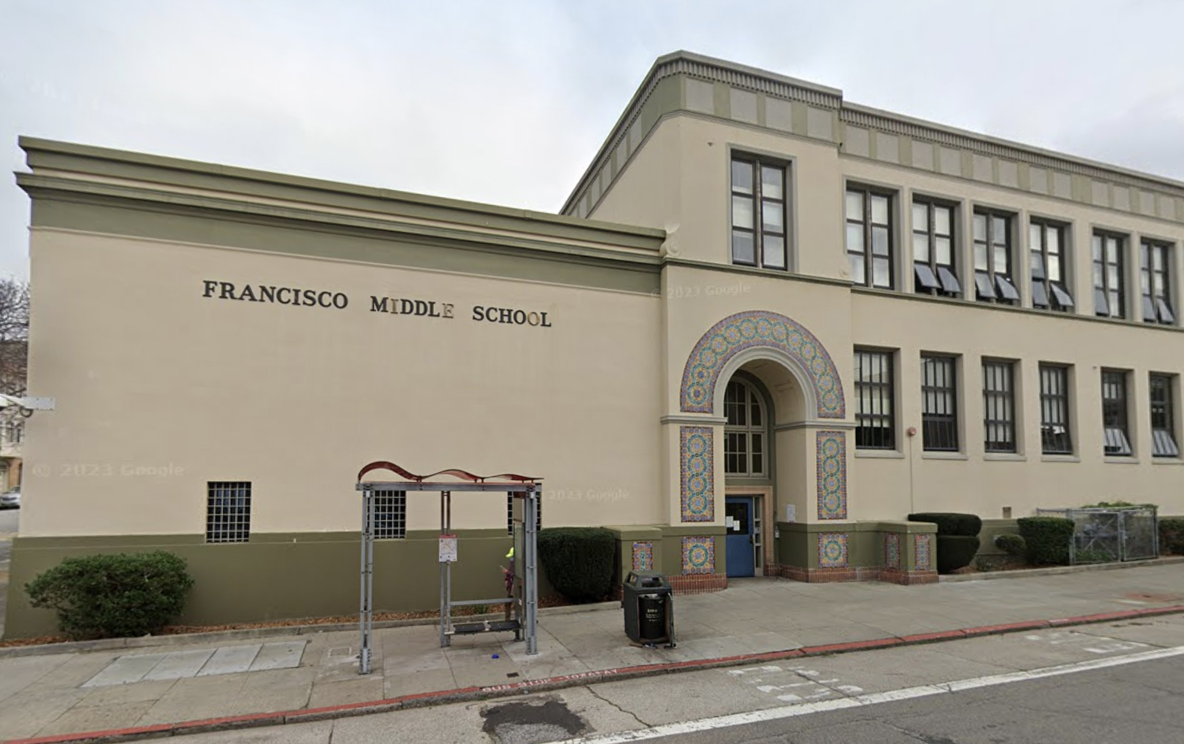 A beige three-story building with "FRANCISCO MIDDLE SCHOOL" written on the side and a decorative arch over the entrance.