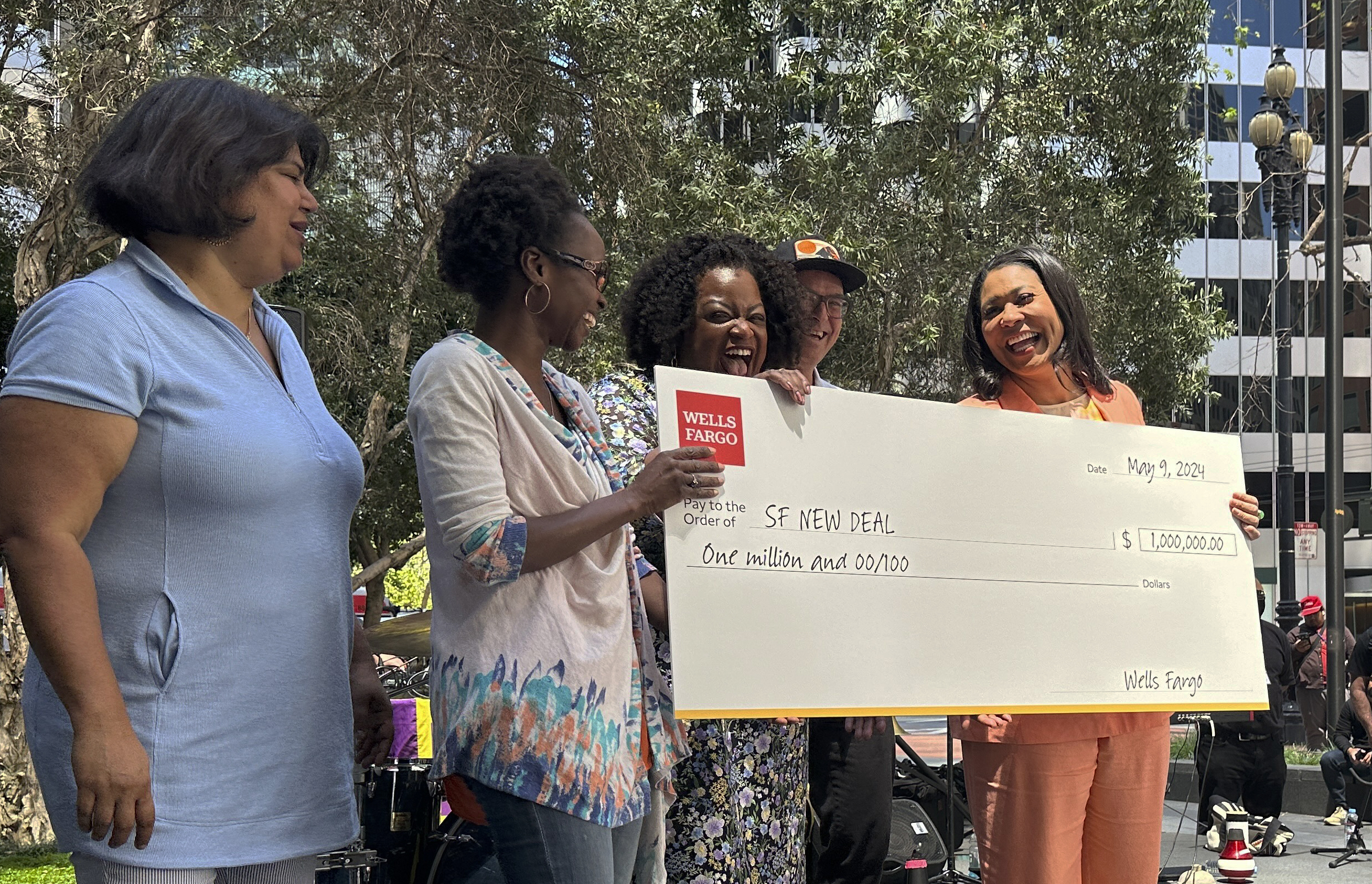 A group of women and one man hold a large check from Wells Fargo bank. 