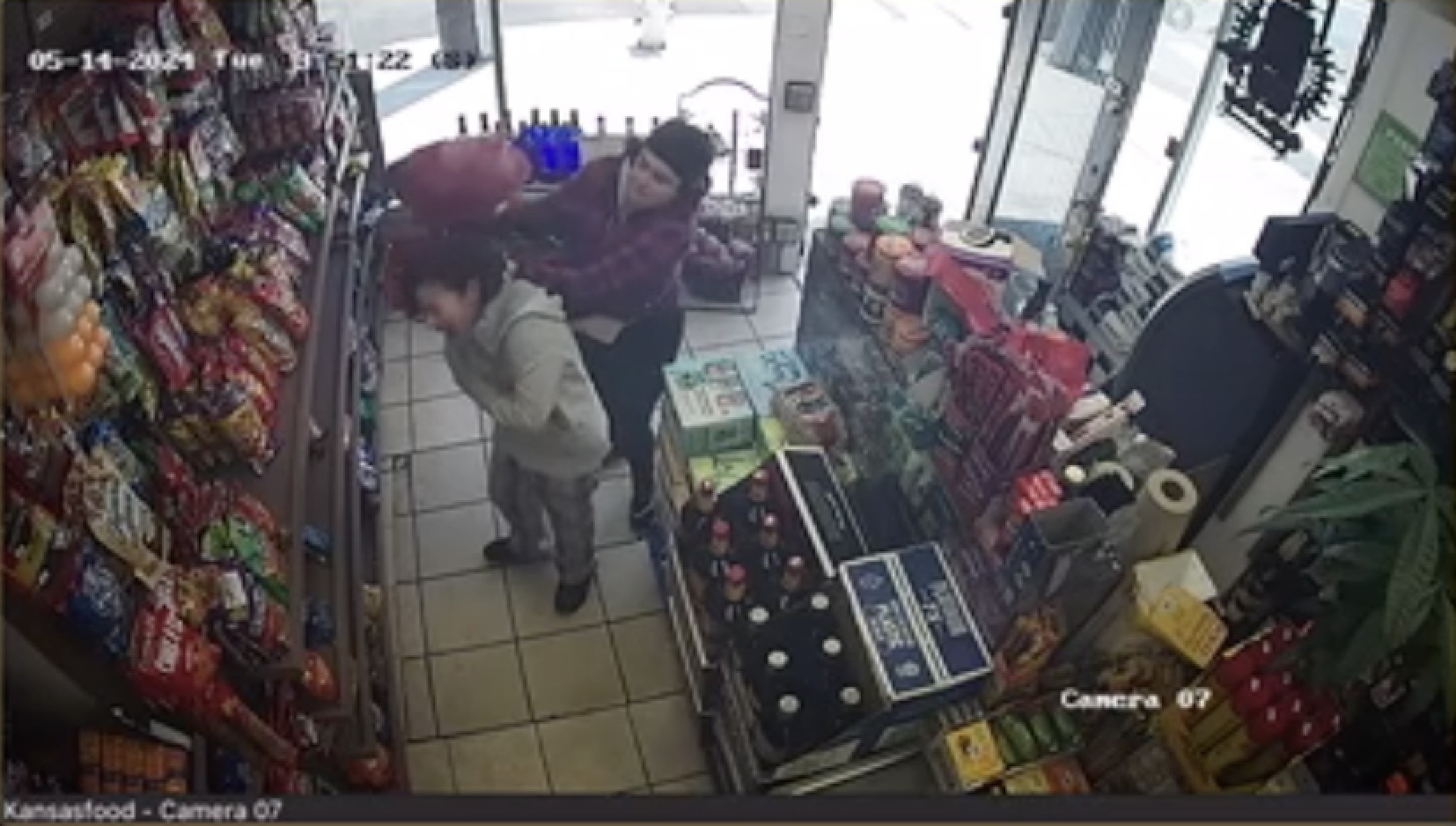 A still from surveillance video shows a woman being attacked by another woman inside a store.