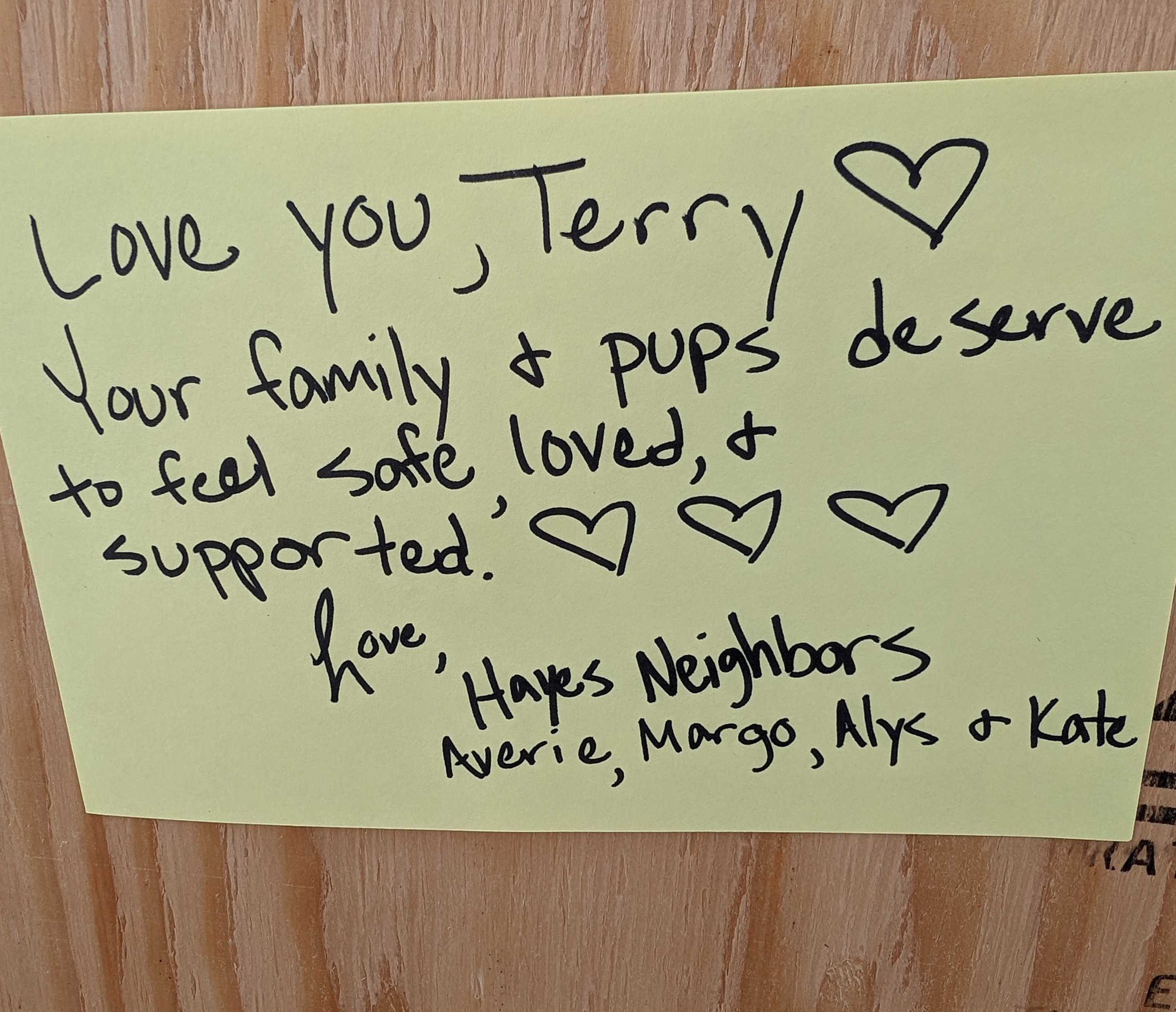 A handwritten note on yellow paper says, &quot;Love you, Terry. Your family &amp; pups deserve to feel safe, loved, &amp; supported.&quot; It's signed by Hayes Neighbors with drawn hearts.