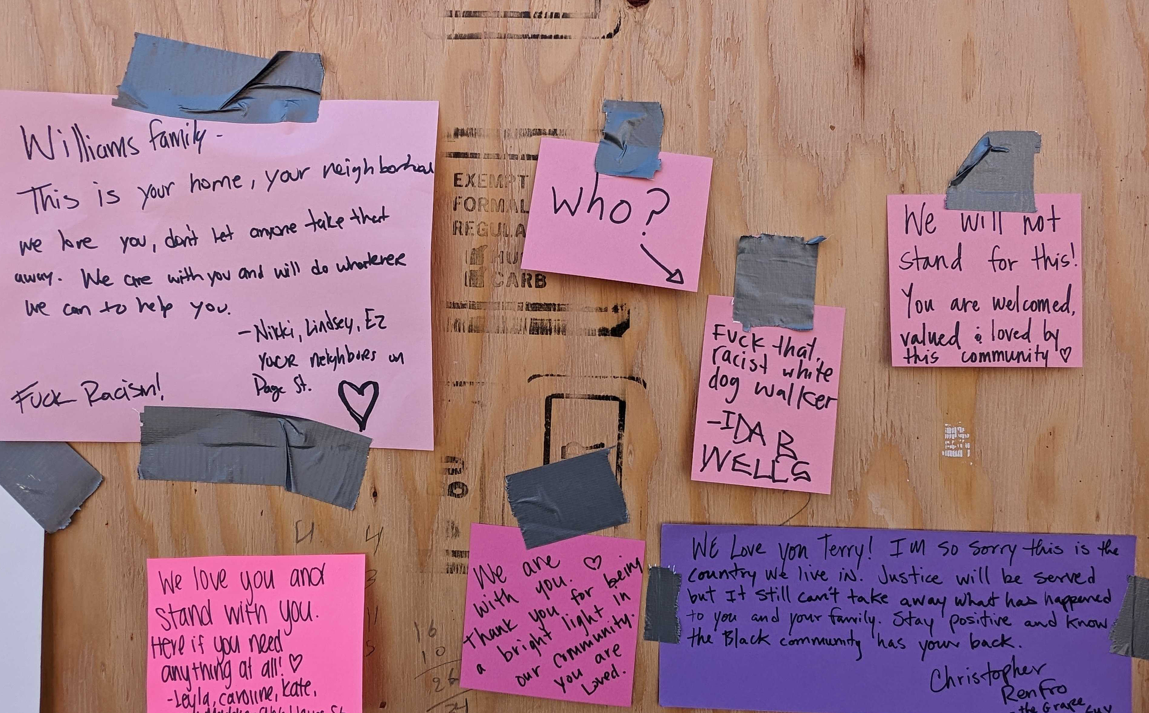 A wooden board has several messages written on pink and purple sticky notes. The notes express support against racism, offering love and solidarity to the Williams family. Duct tape secures the notes.