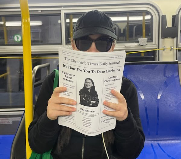 A person in sunglasses and baseball cap riding a Muni bus holds a humorous flyer urging readers to date a journalist named Christina.