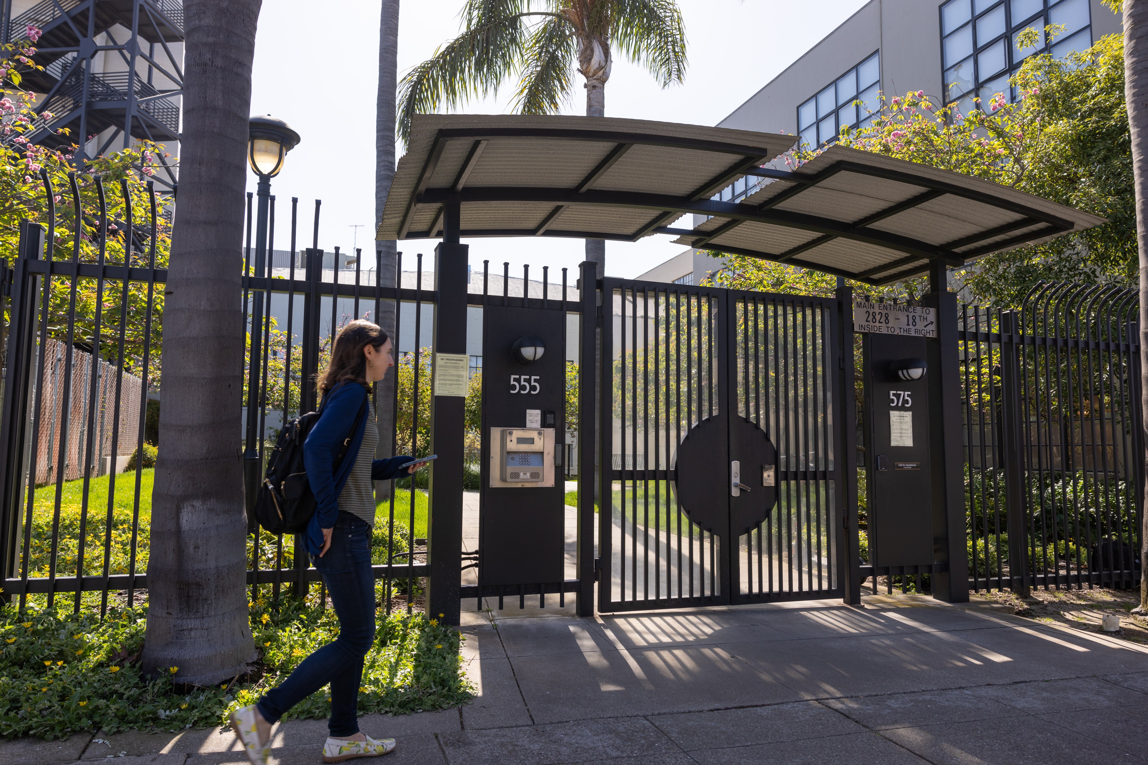 A woman is seen walking past a gate in a photo.