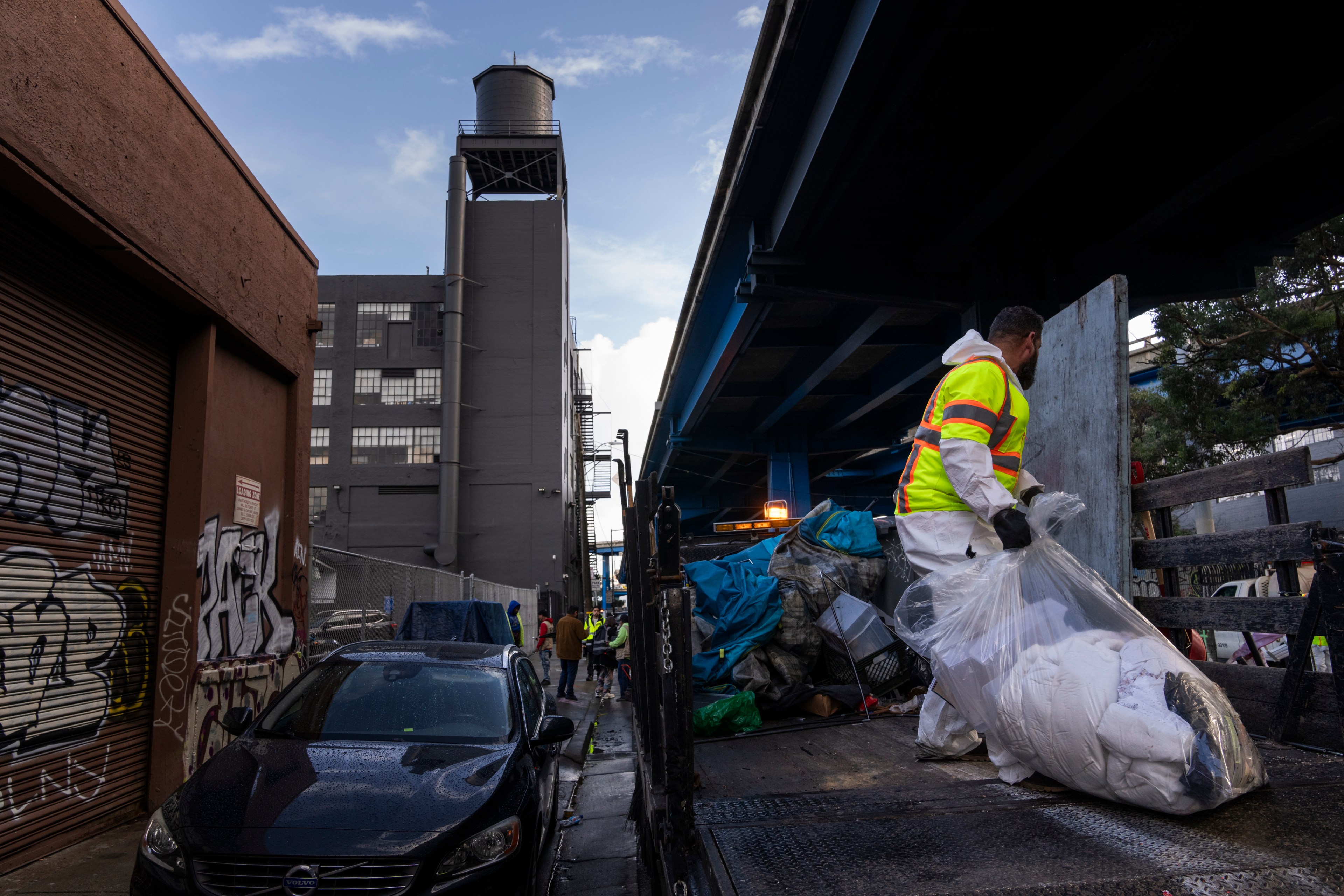 A city worker clears a tent encampment in SoMa