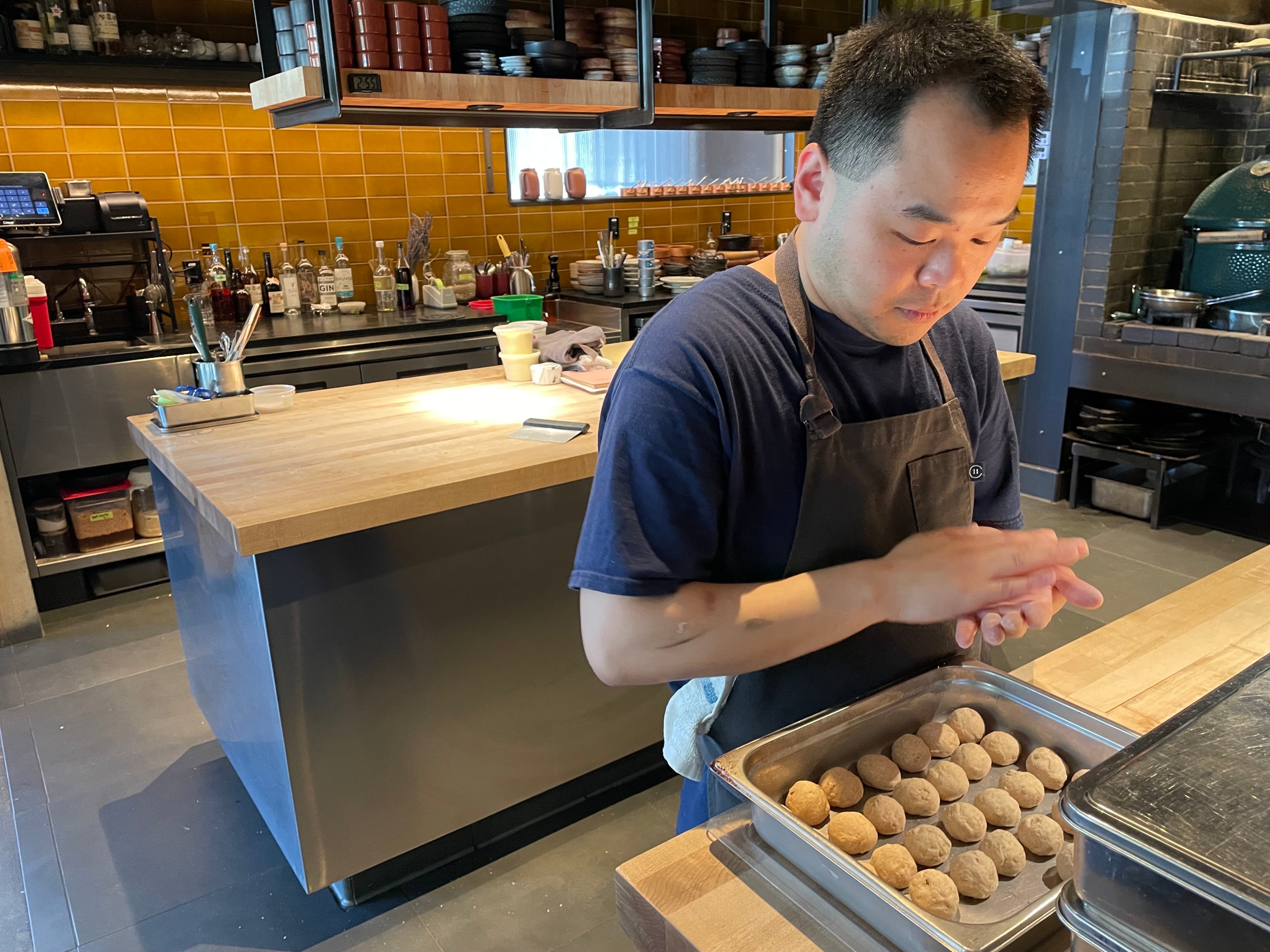 A man rolls balls of dough.