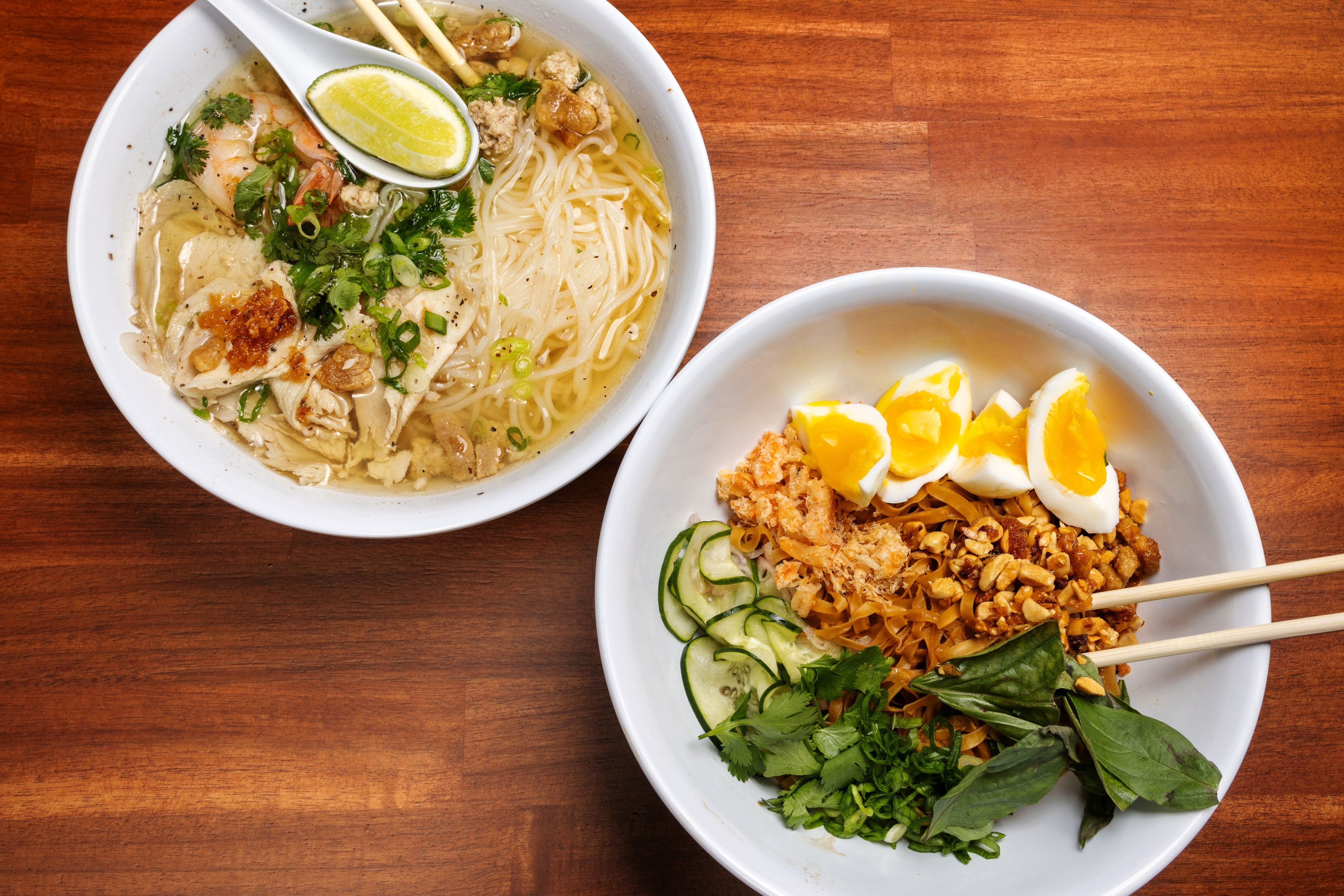 The Kuy Teav Phnom Penh noodle soup (left) and Mee Kola bowl sit on a table in Lunette Cambodia