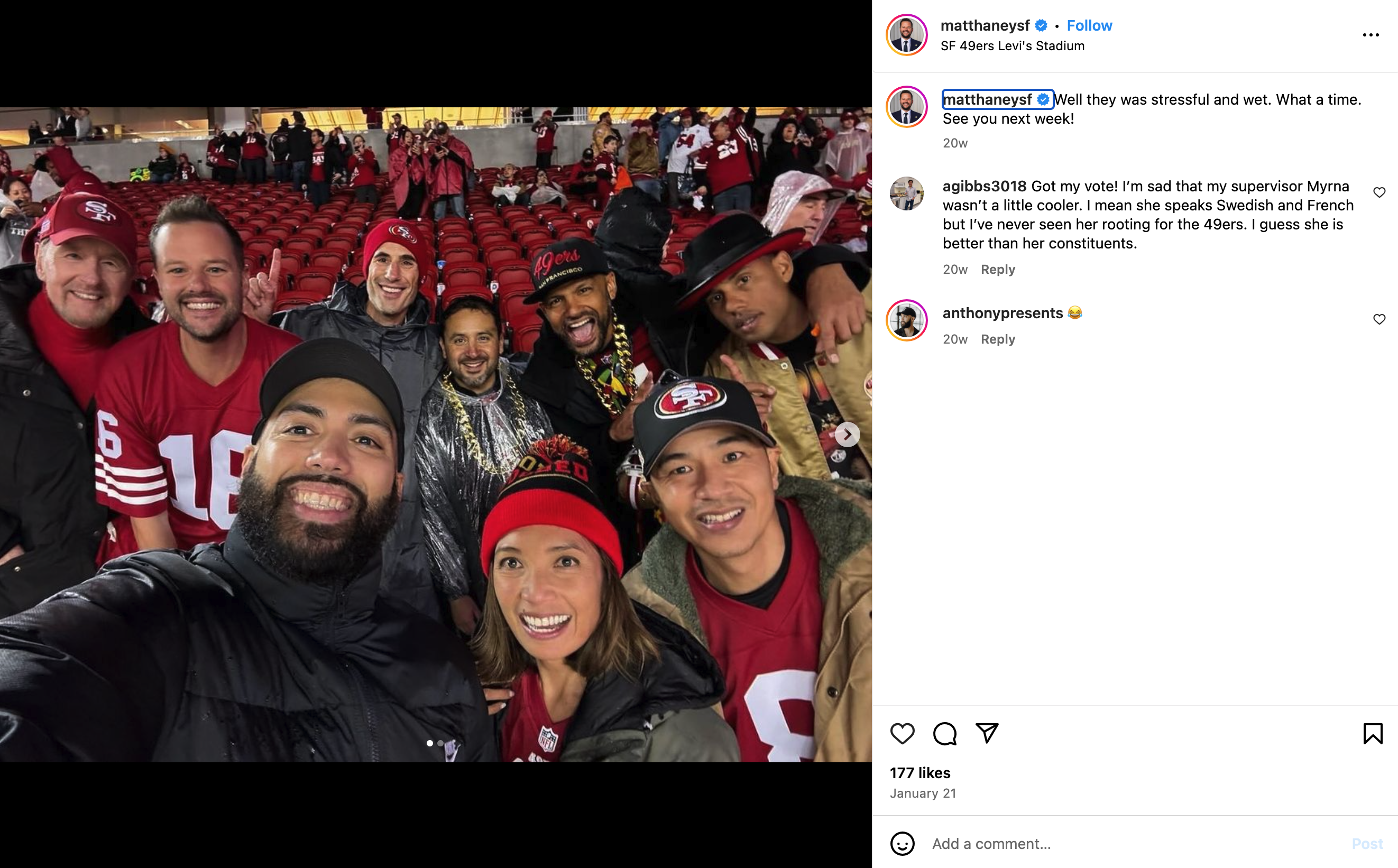 A group of nine people is smiling and posing for a selfie at a sports stadium. They are wearing 49ers gear, and the stands in the background have scattered fans.
