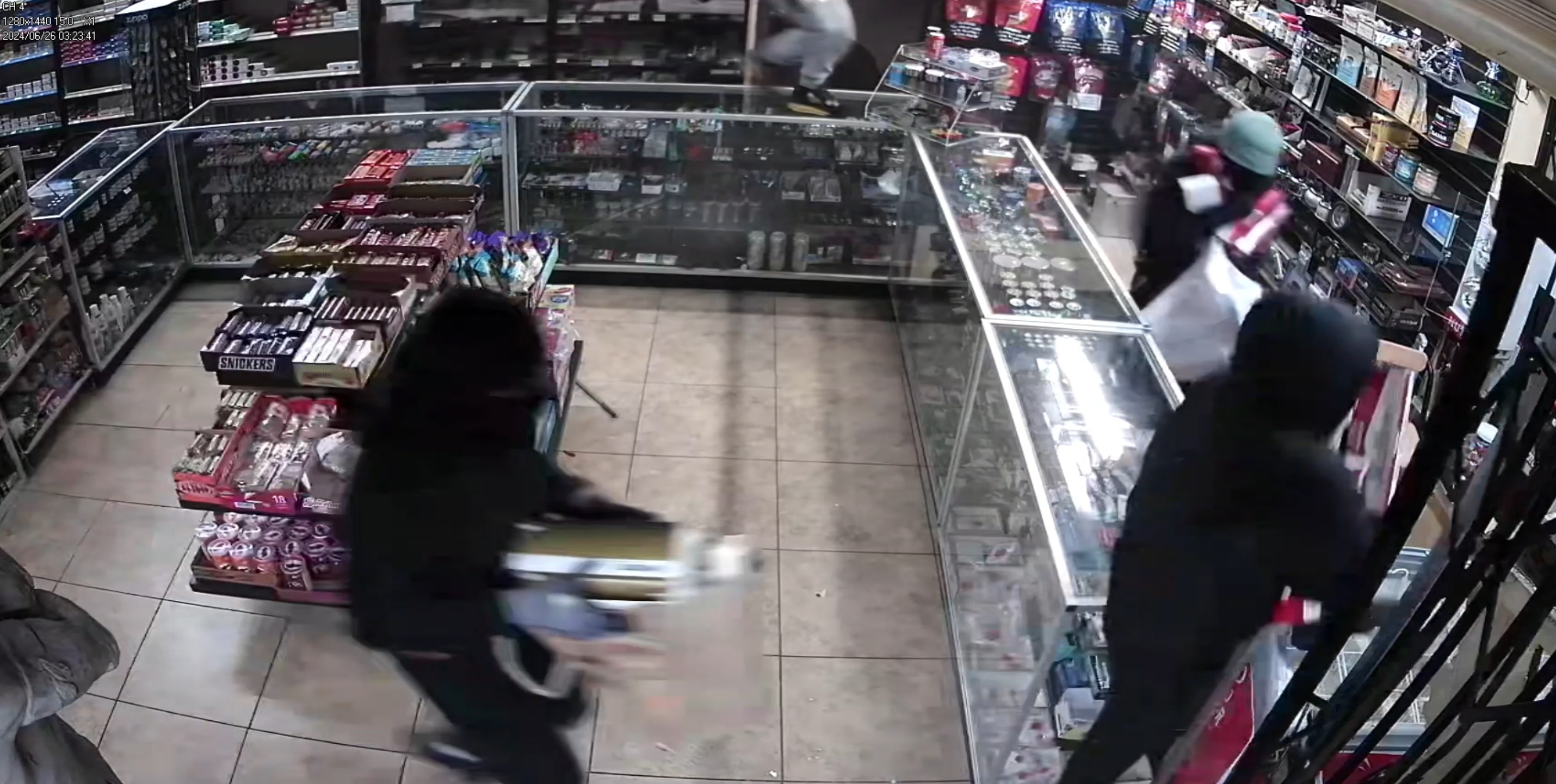 A still taken from surveillance video shows thieves ransacking a smoke shop.
