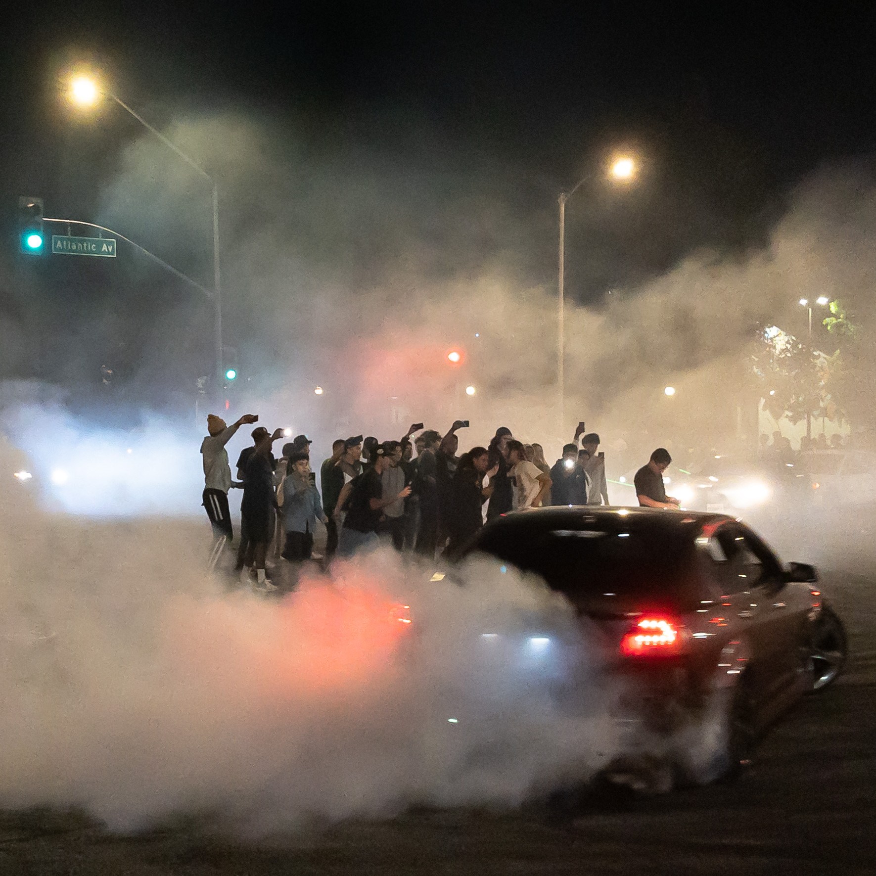 A car drifts around spectators gathered in the middle of the intersection during an early morning street sideshow at Compton Boulevard and Atlantic Avenue in East Compton on Sunday, Aug. 14, 2022. Takeovers are a growing trend and residents say that law enforcement are not doing enough to stop them. There have been some residents who say that the events are dangerous and keep them up at night. Some spectators said they feel like they're not bothering anyone and they only happen at night when the streets are empty.