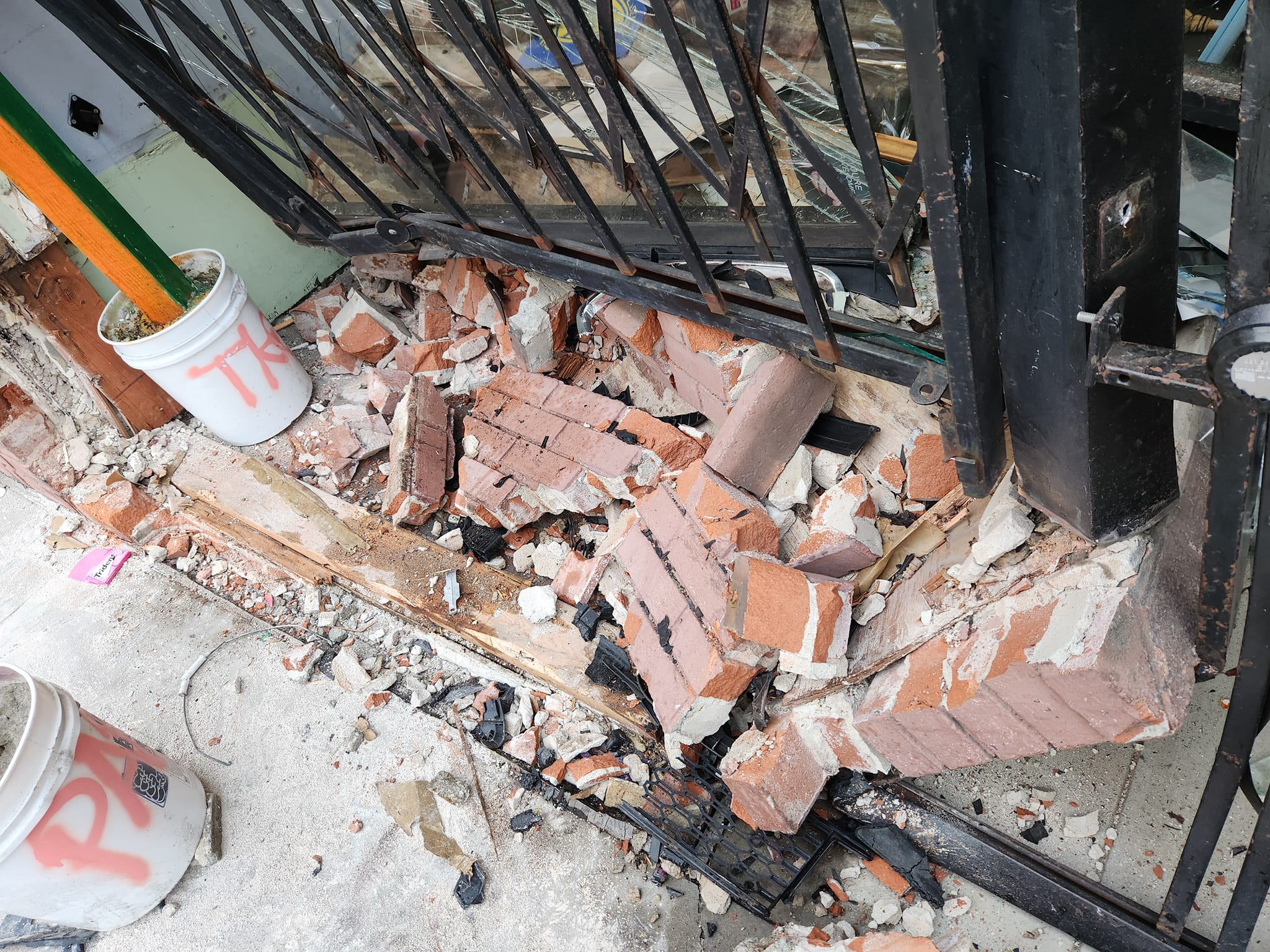 Loose bricks are down on the sidewalk outside a metal-gated bicycle shop after a solo car crash.